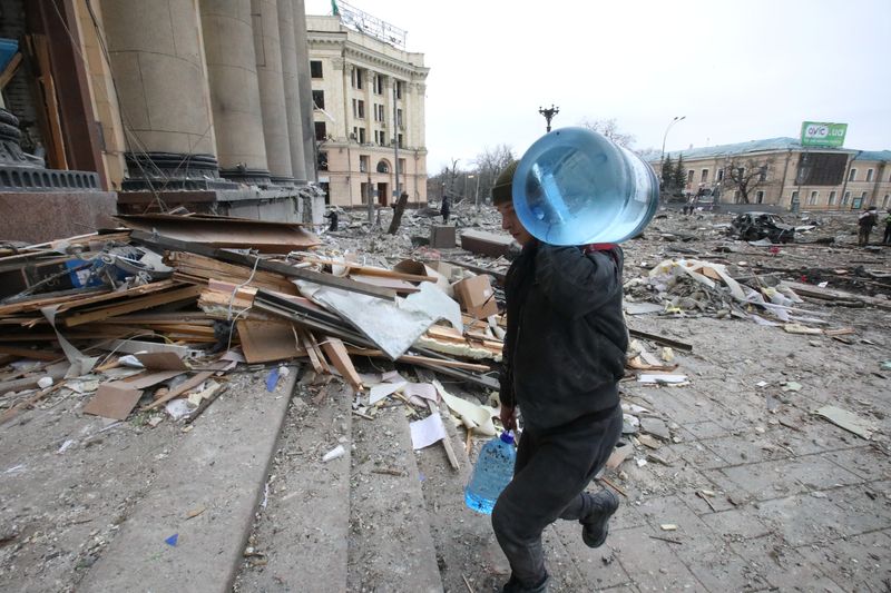 Un hombre lleva agua fuera del edificio de la administración regional, que según las autoridades de la ciudad fue alcanzado por un ataque con misiles, en el centro de Járkow, Ucrania, 1 de marzo de 2022 (Reuters)