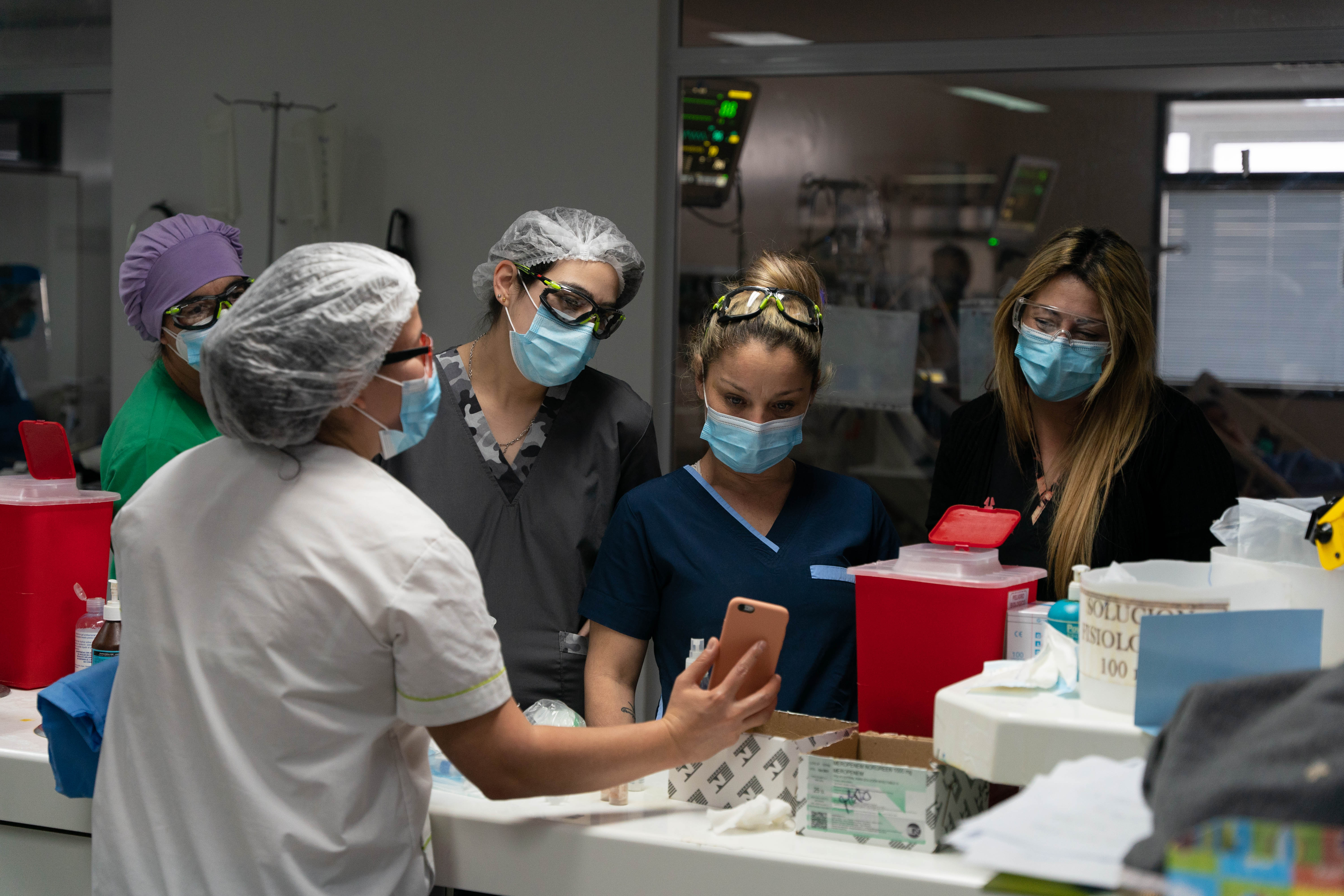 Juliana Torquati, Deborah Russo y dos enfermeras más miran una imagen del teléfono de su compañera. Todo lo que hablan mientras están ahí es relacionado a los pacientes.