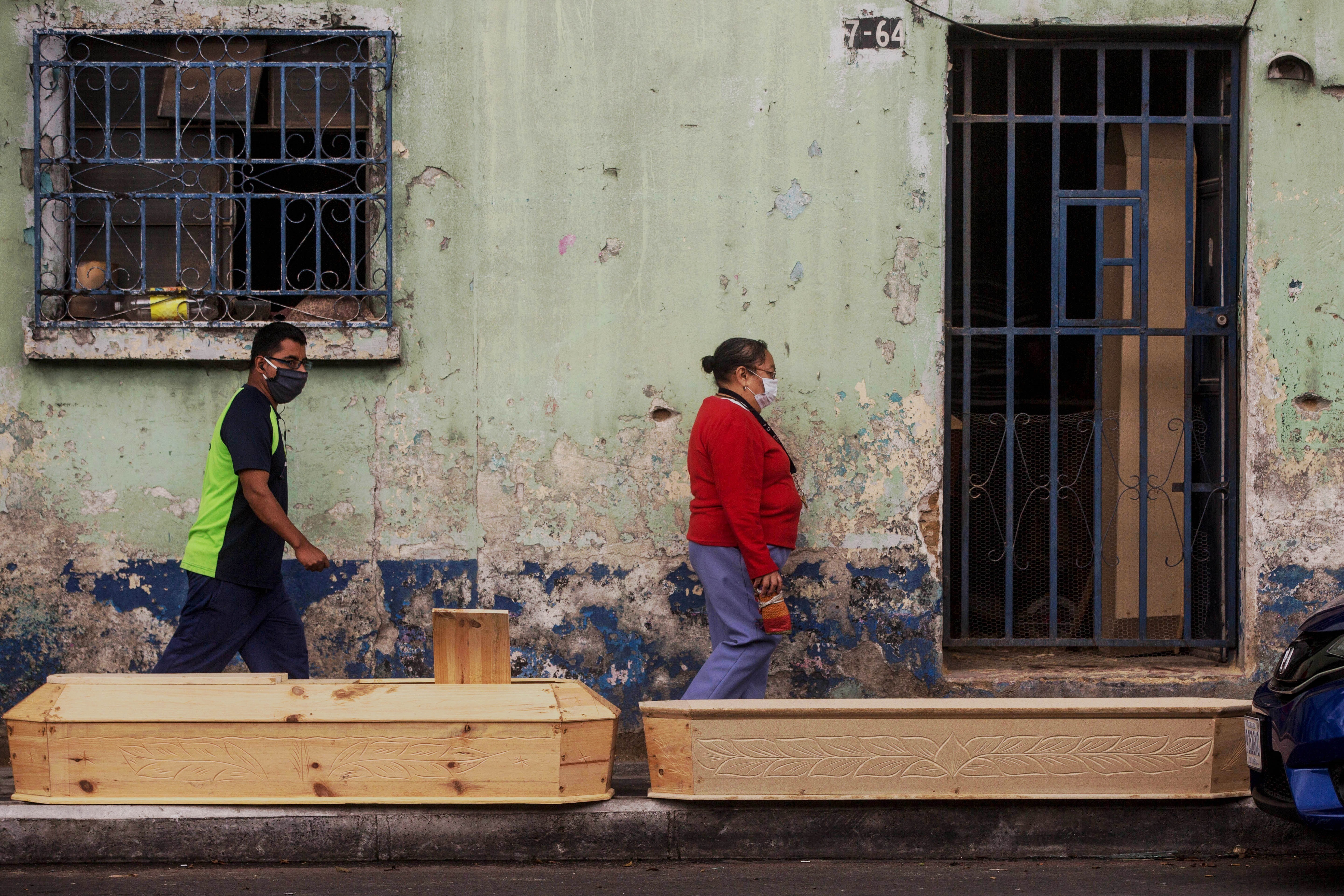 Personas pasan frente a los féretros de la fábrica Estrada en ciudad de Guatemala (EFE/Esteban Biba)