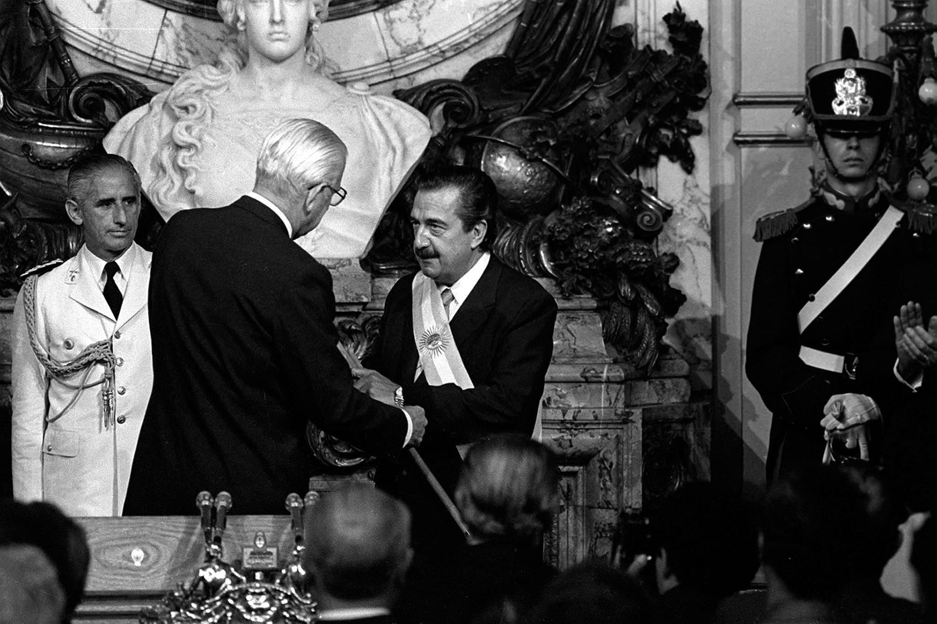Raúl Alfonsín recibe los atributos de manos de Reinaldo Bignone, último presidente de facto de la historia argentina (Foto: Archivo /Alberto Haliasz/Carlos Ventura)