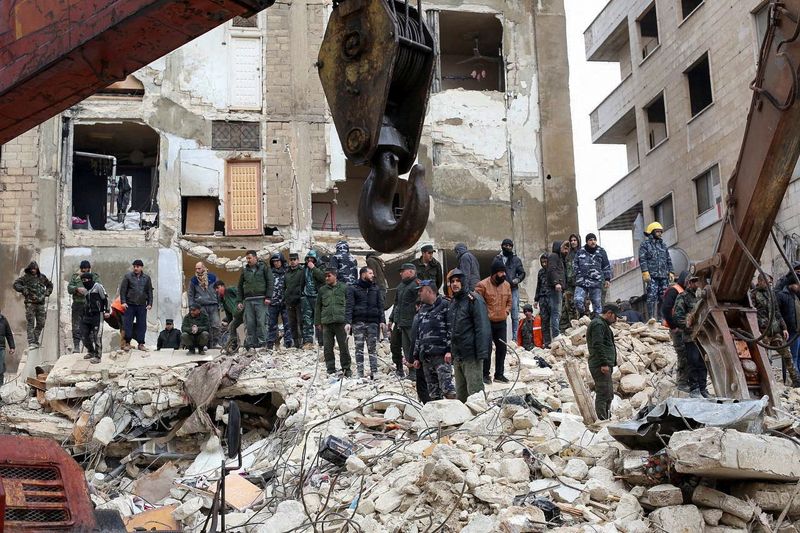 Rescatistas usan maquinaria pesada en busca de supervivientes en el lugar donde se derrumbó un edificio, tras un terremoto, en Hama, Siria. 