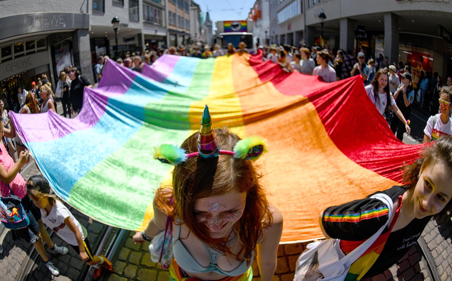 Los participantes del desfile del orgullo Christopher Street Day llevan una bandera con los colores del arco iris mientras caminan por las calles de Friburgo, en el sur de Alemania, el 23 de junio de 2018