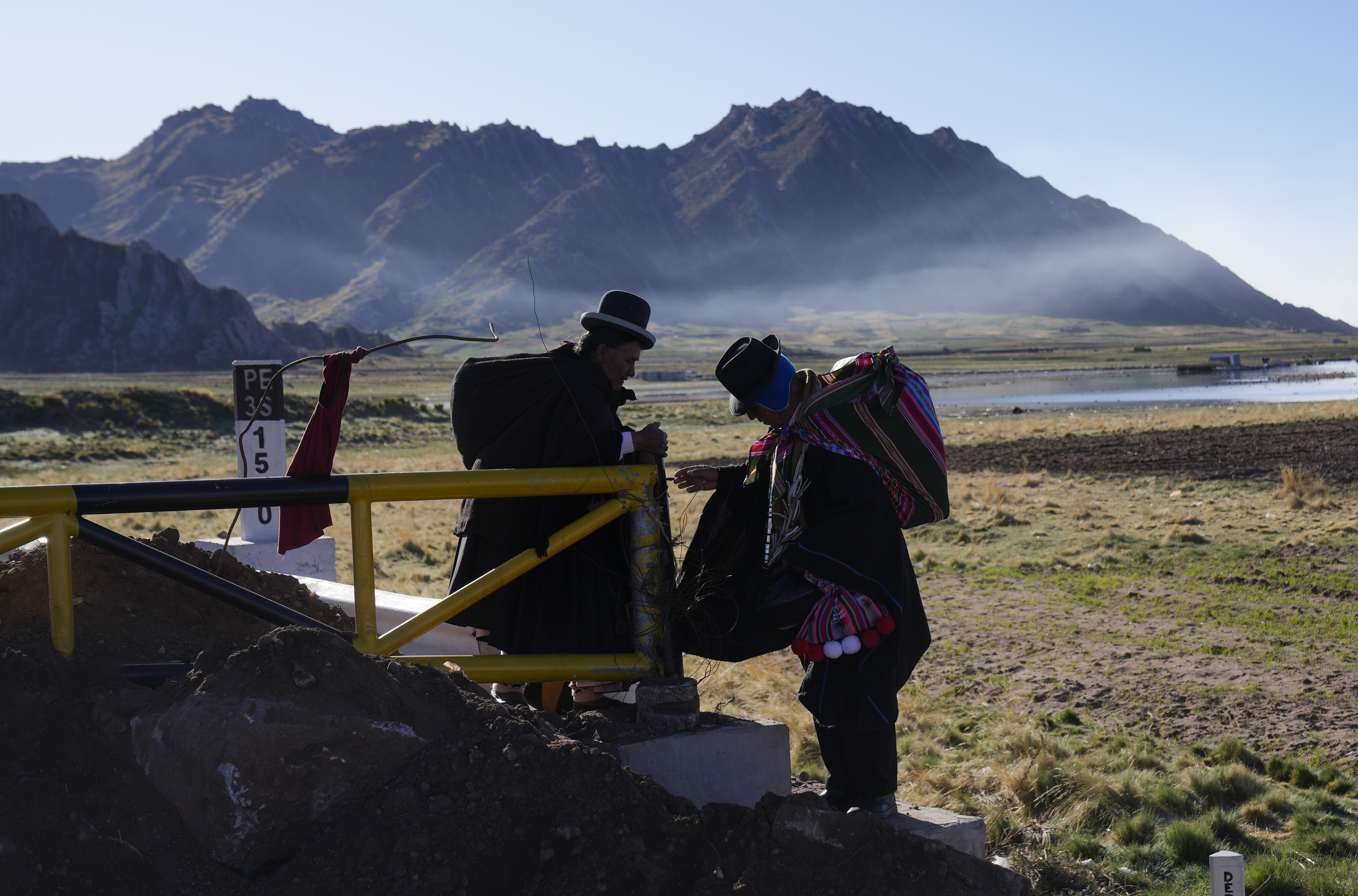 Indígenas aymaras caminan alrededor de una barricada levantada por manifestantes antigubernamentales en Desaguadero, Perú, mientras cruzan la frontera de Bolivia a Perú, el viernes 13 de enero de 2023. (AP Foto/Juan Karita)