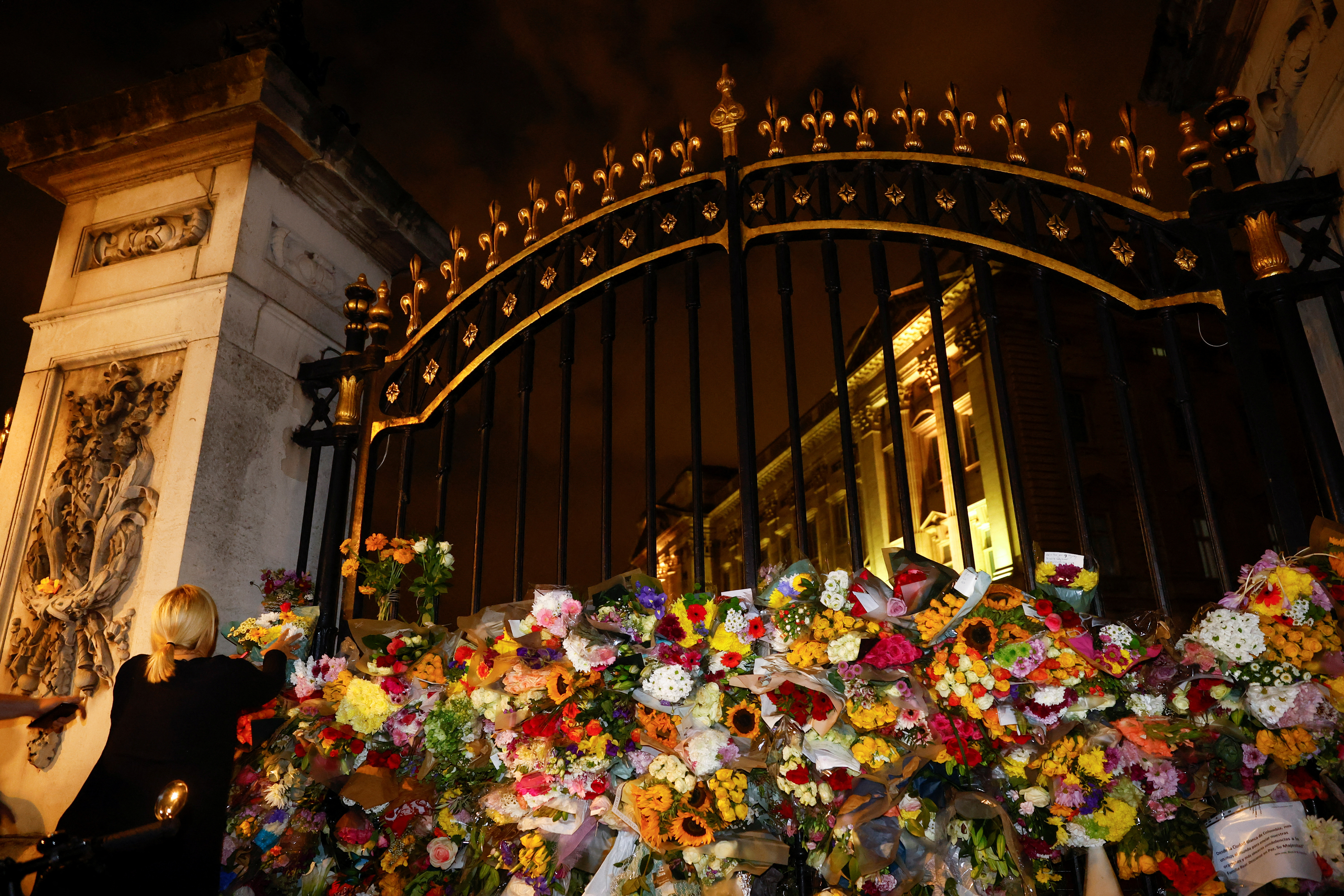 Una mujer coloca flores fuera del Palacio de Buckingham el 9 de septiembre de 2022 (REUTERS/Andrew Boyers)