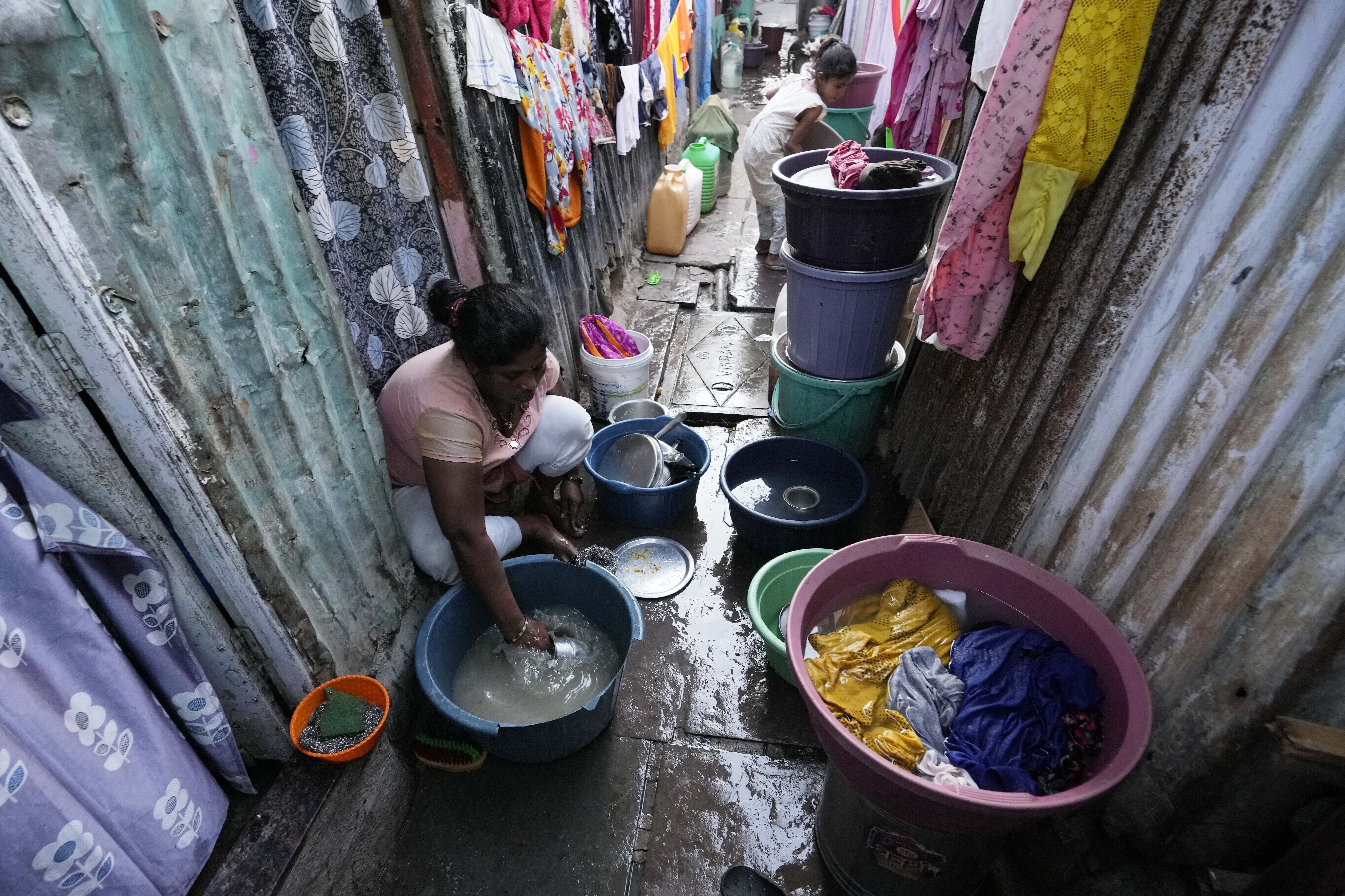 Una mujer friega utensilios de cocina en el exterior de su casa en una barriada humilde en la víspera del Día Mundial del Agua, en Mumbai, India, el 21 de marzo de 2023. (AP Foto/Rajanish Kakade)