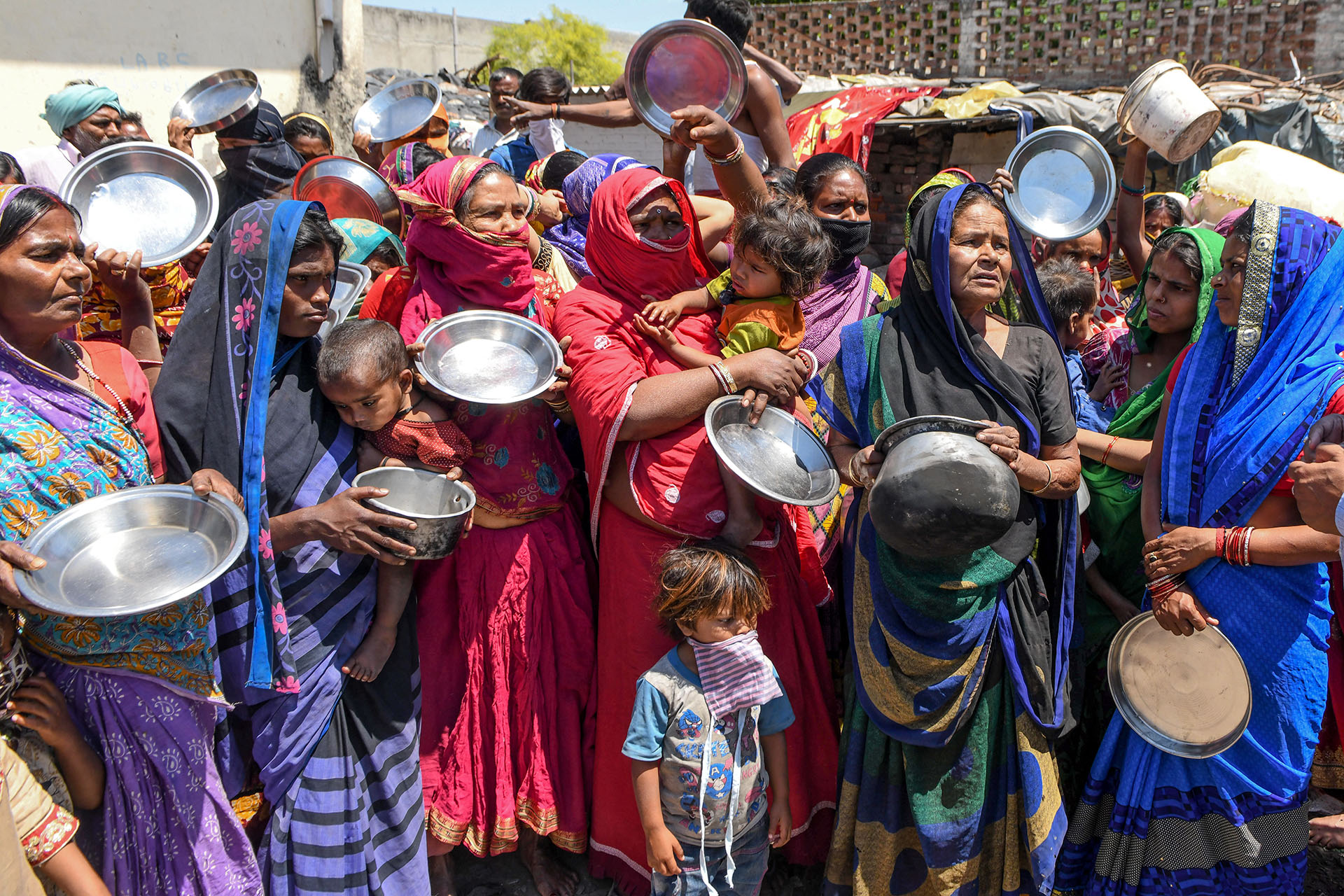Trabajadores migrantes y familias de los estados de Bihar y Uttar Pradesh sostienen utensilios de cocina mientras protestan contra el gobierno por la falta de alimentos en un área de tugurios en Amritsar el 22 de abril de 2020 (Foto de NARINDER NANU / AFP)
