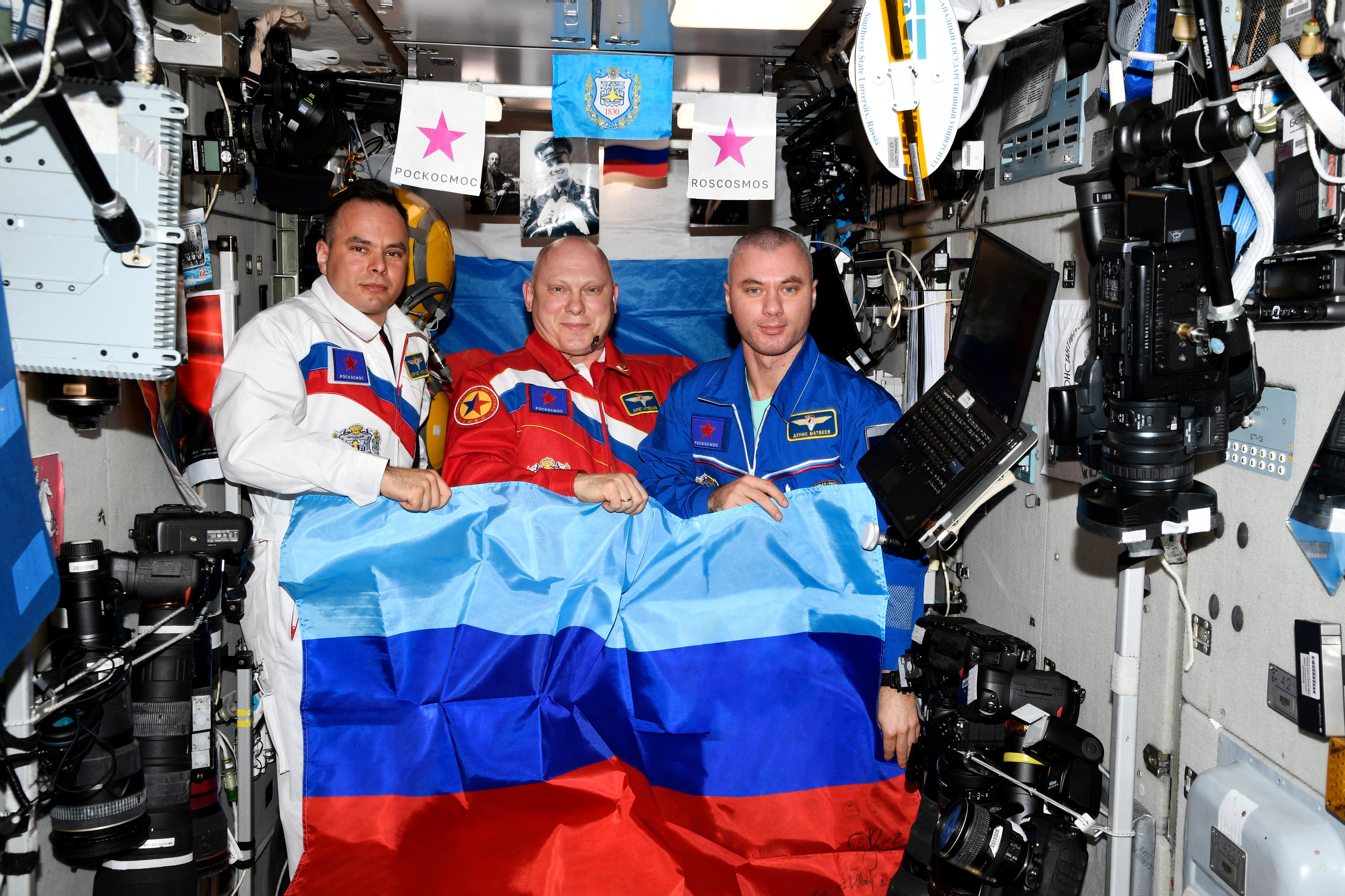 นักบินอวกาศชาวรัสเซีย Oleg Artemiev, Denis Matveev และ Sergey Korsakov สวมธงชาติสาธารณรัฐประชาชน Lugansk ที่ประกาศตัวเองบนสถานีอวกาศนานาชาติ (ISS) ในภาพนี้เผยแพร่ 4 กรกฎาคม 2022 (Roscosmos/REUTERS)