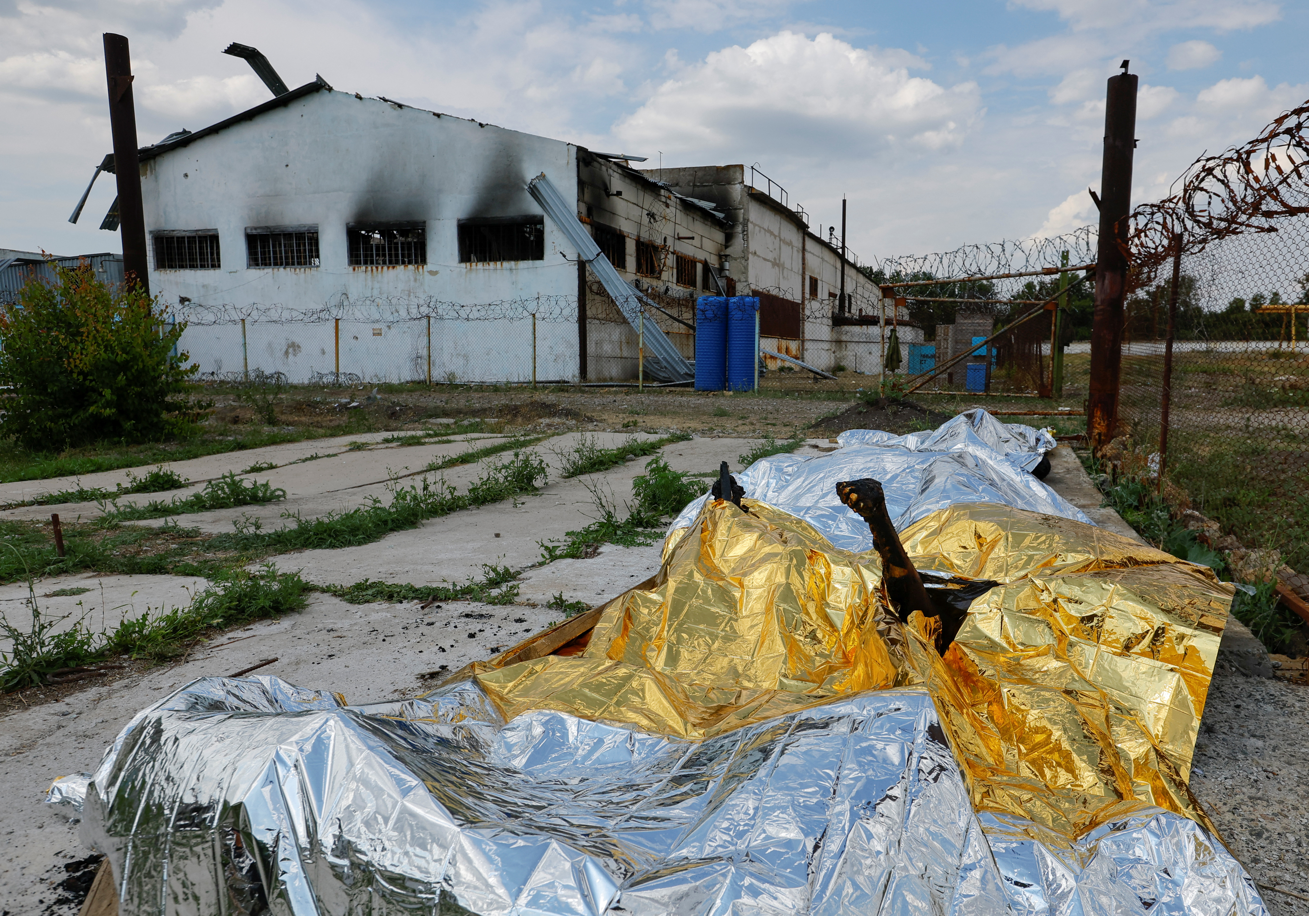 IMÁGENES SENSIBLES: Cuerpos quemados de detenidos yacen cubiertos tras el bombardeo en un centro de detención preventiva en el curso del conflicto entre Ucrania y Rusia, en el asentamiento de Olenivka en la región de Donetsk, Ucrania 29 de mayo de 2022. REUTERS/Alexander Ermochenko