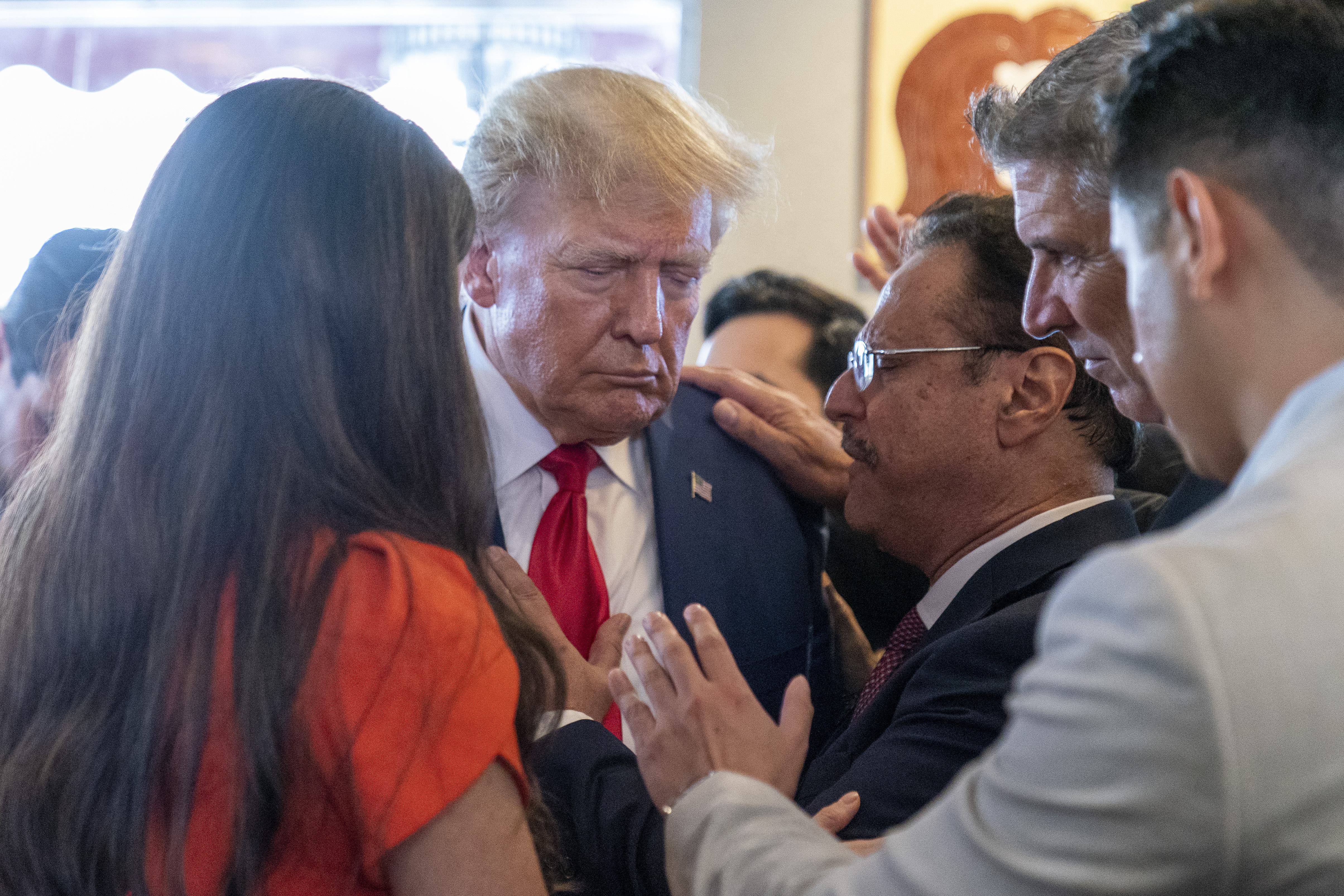 El ex presidente Donald Trump reza con el pastor Mario Bramnick, tercero desde la derecha, y otras personas en el restaurante Versailles el martes 13 de junio de 2023 en Miami (AP Photo/Alex Brandon)