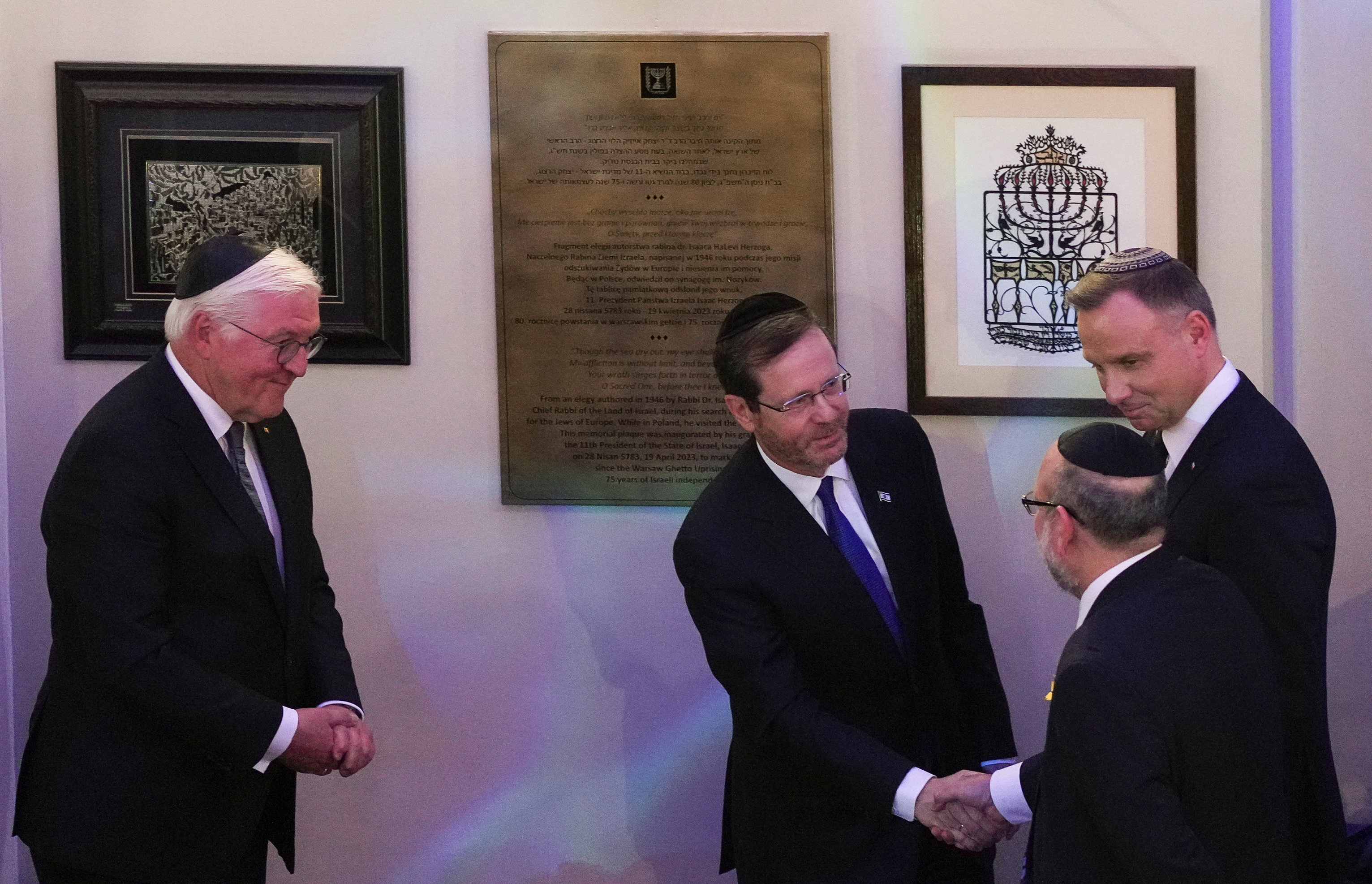 El presidente israelí, Isaac Herzog, junto al presidente alemán, Frank-Walter Steinmeier, y el presidente polaco, Andrzej Duda, se dan la mano con Michael Schudrich, Gran Rabino de Polonia, tras la inauguración de una placa conmemorativa de la visita de Isaac Herzog. REUTERS/Aleksandra Szmigiel