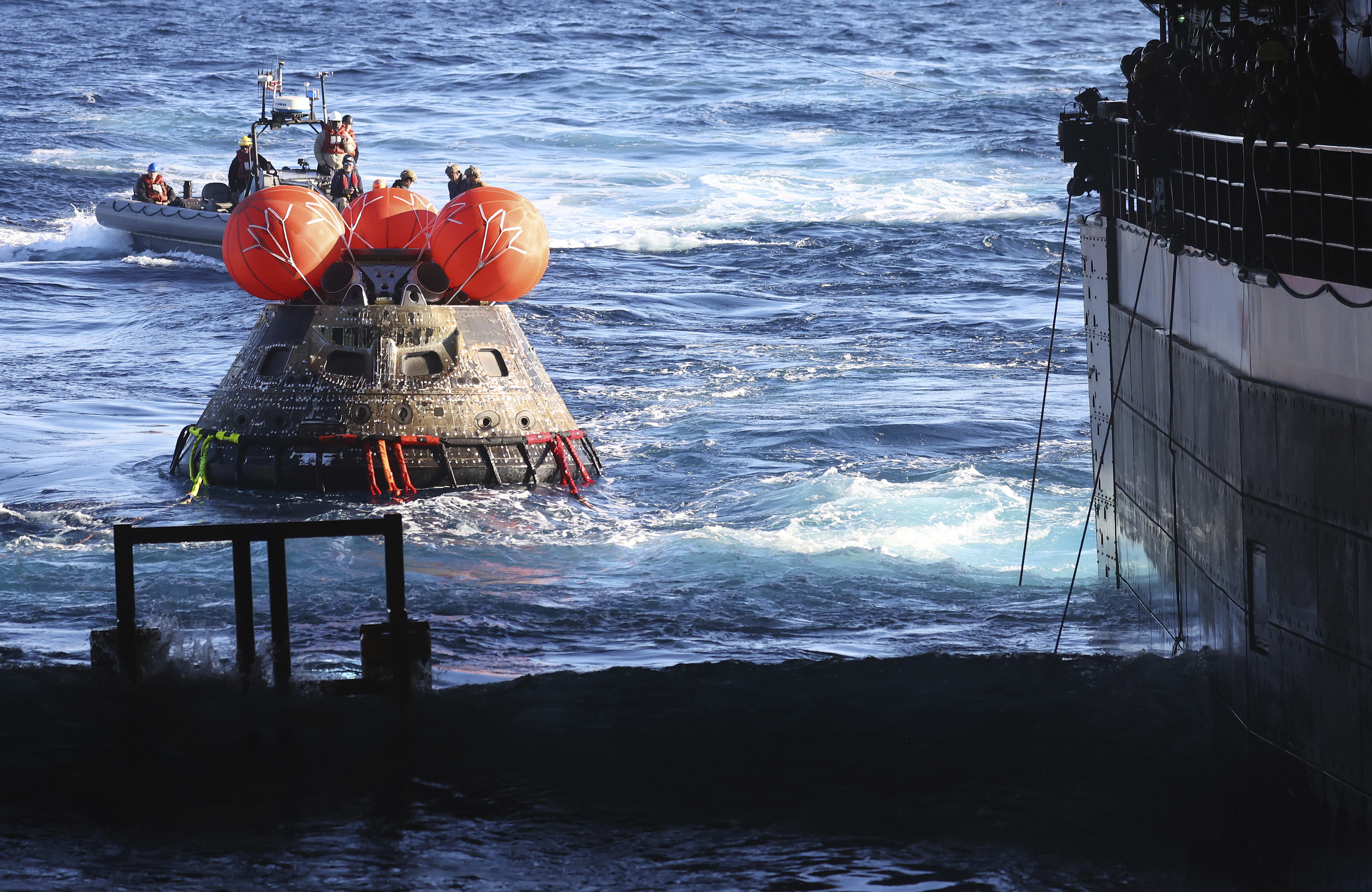 La cápsula Orión de la NASA es llevada a la cubierta del USS Portland después del regreso exitoso de la misión lunar no tripulada Artemis 1, el domingo 11 de diciembre de 2022, en el Océano Pacífico, frente a las costas de Baja California, México. (Mario Tama/Pool Photo via AP)