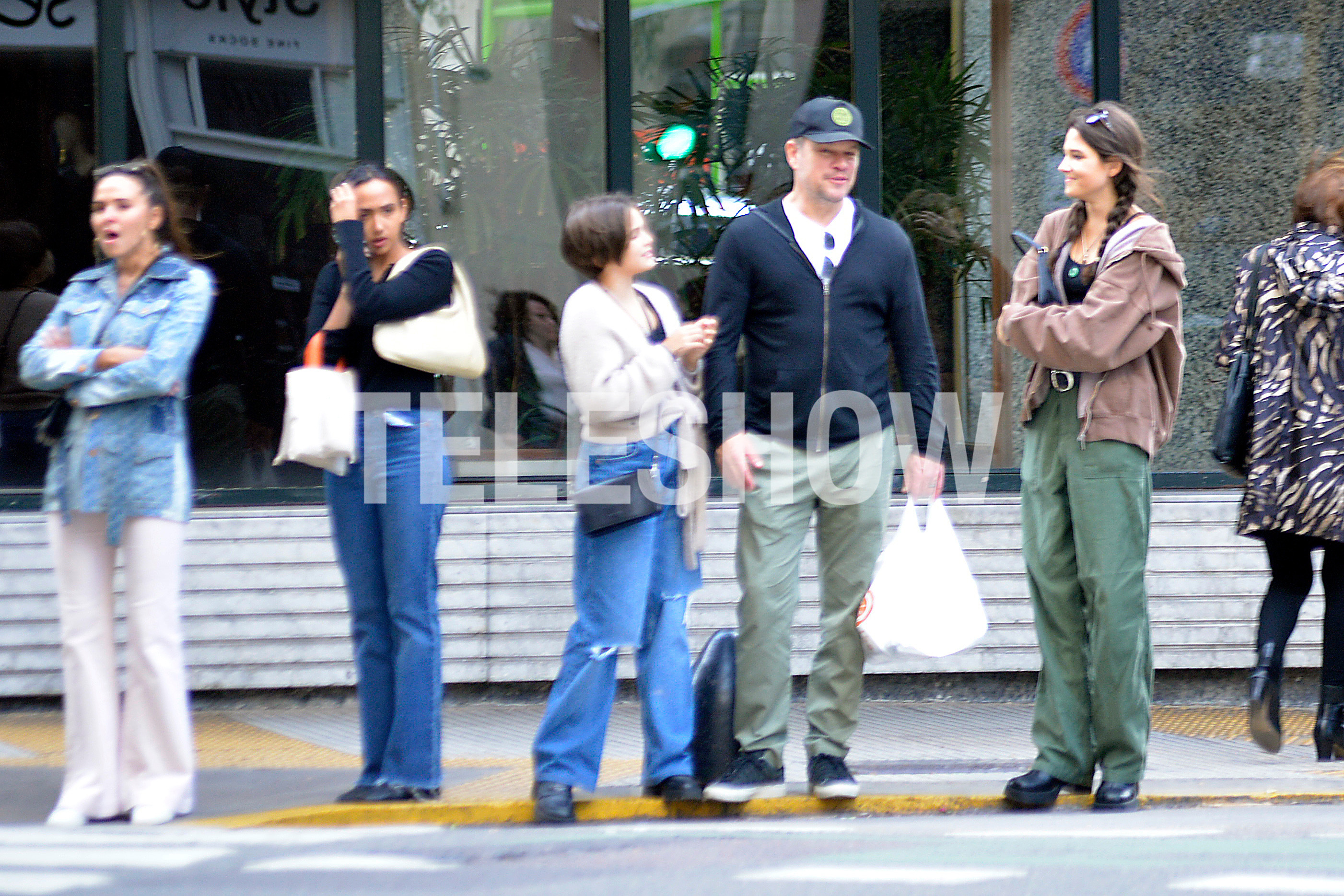De camisa de jean, Luciana Barroso, y Alexia hablando por teléfono mientras Matt Damon charla con dos de sus hijas