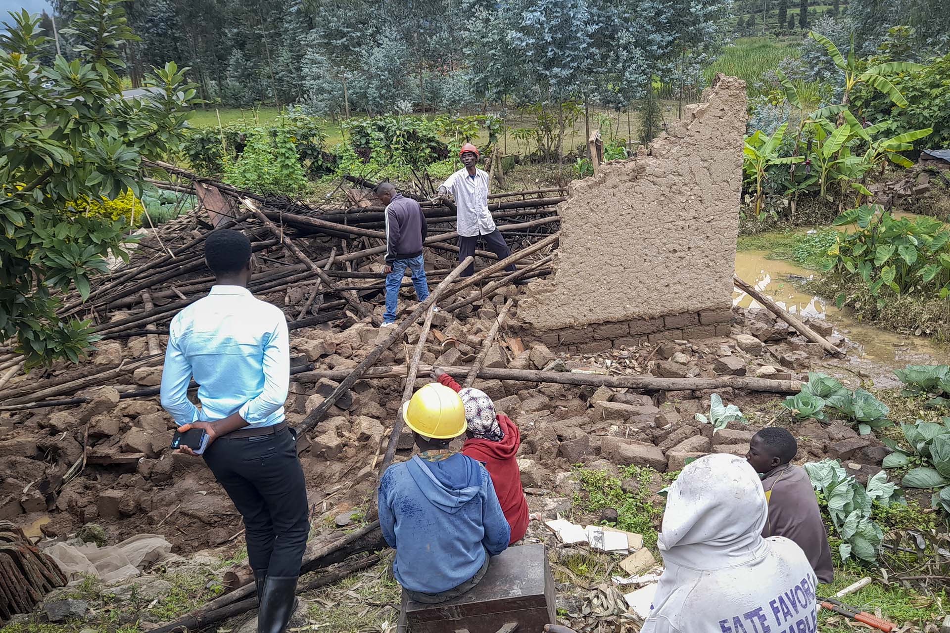 Varias personas se reúnen junto a un edificio derrumbado tras las inundaciones (AP Photo/Rachid Bugirinfura)