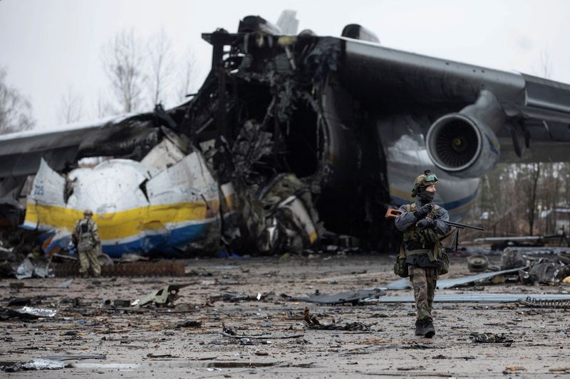 Un miembro del servicio ucraniano camina delante del avión de carga Antonov An-225 Mriya, el más grande del mundo, destruido por las tropas rusas en medio del ataque de Rusia a Ucrania