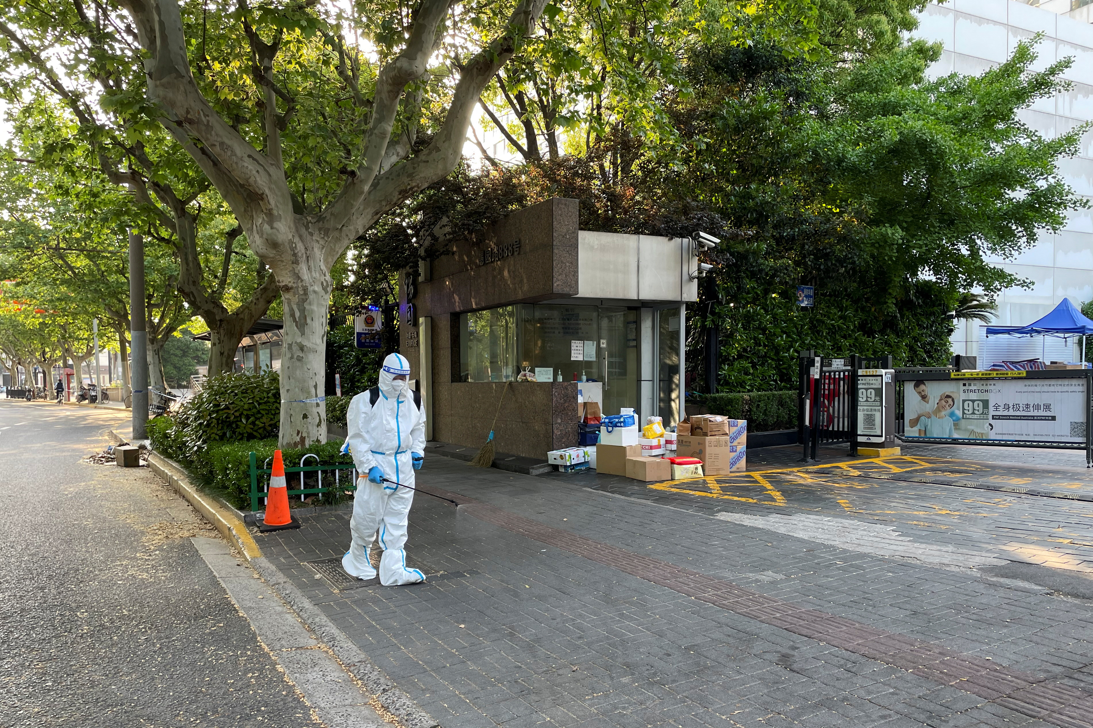 Un trabajador con traje protector desinfecta el suelo frente a un complejo residencial en medio del brote de la enfermedad coronavirus (COVID-19) en Shanghái, China, 21 de abril de 2022. REUTERS/Brenda Goh
