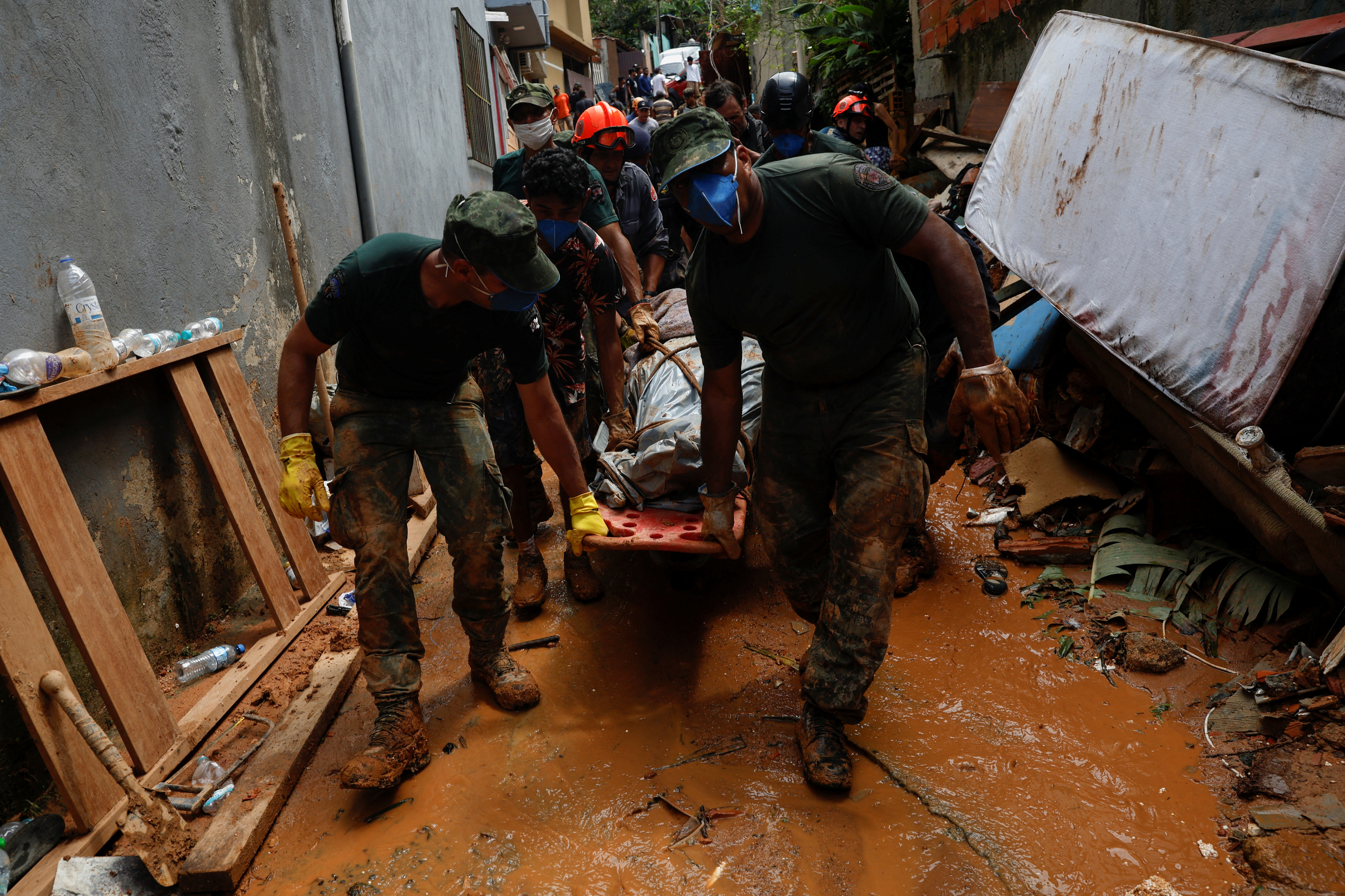 Voluntarios, bomberos, oficiales del ejército y un guardia civil llevan el cuerpo de una mujer que murió en uno de los sitios de deslizamientos de tierra (REUTERS/Amanda Perobelli)