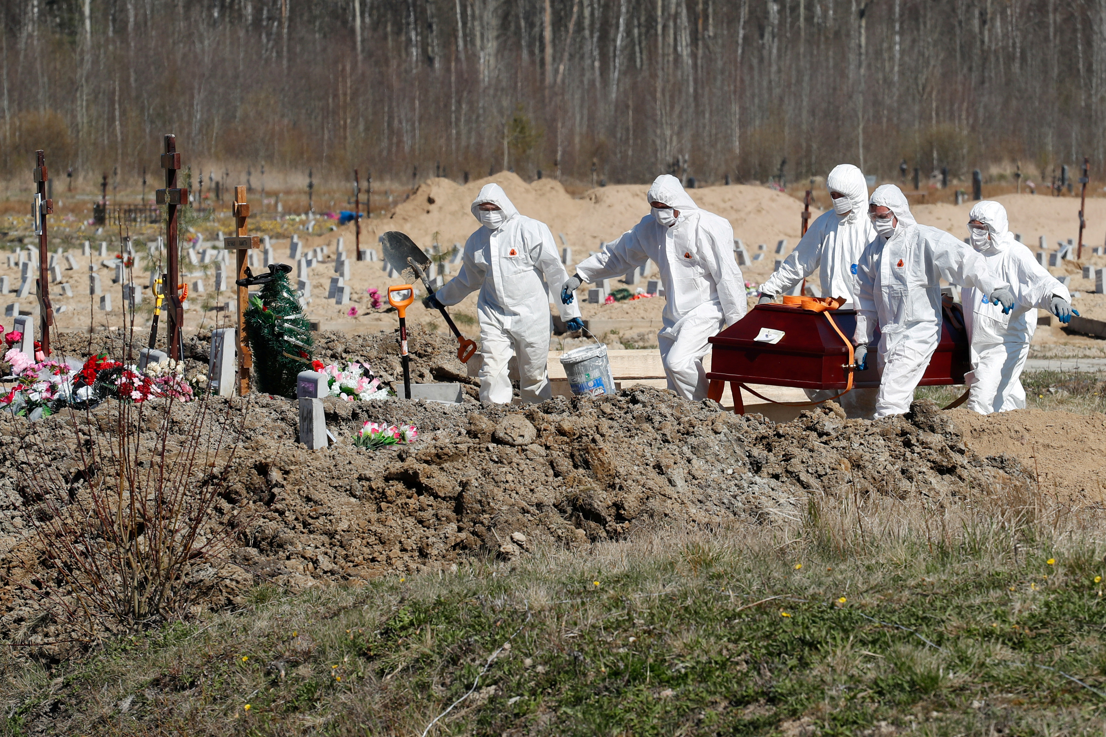 Excavadores de tumbas llevan un ataúd con una víctima de coronavirus en un cementerio en las afueras de San Petersburgo, Rusia, el 5 de mayo de 2020. (REUTERS/Anton Vaganov)
