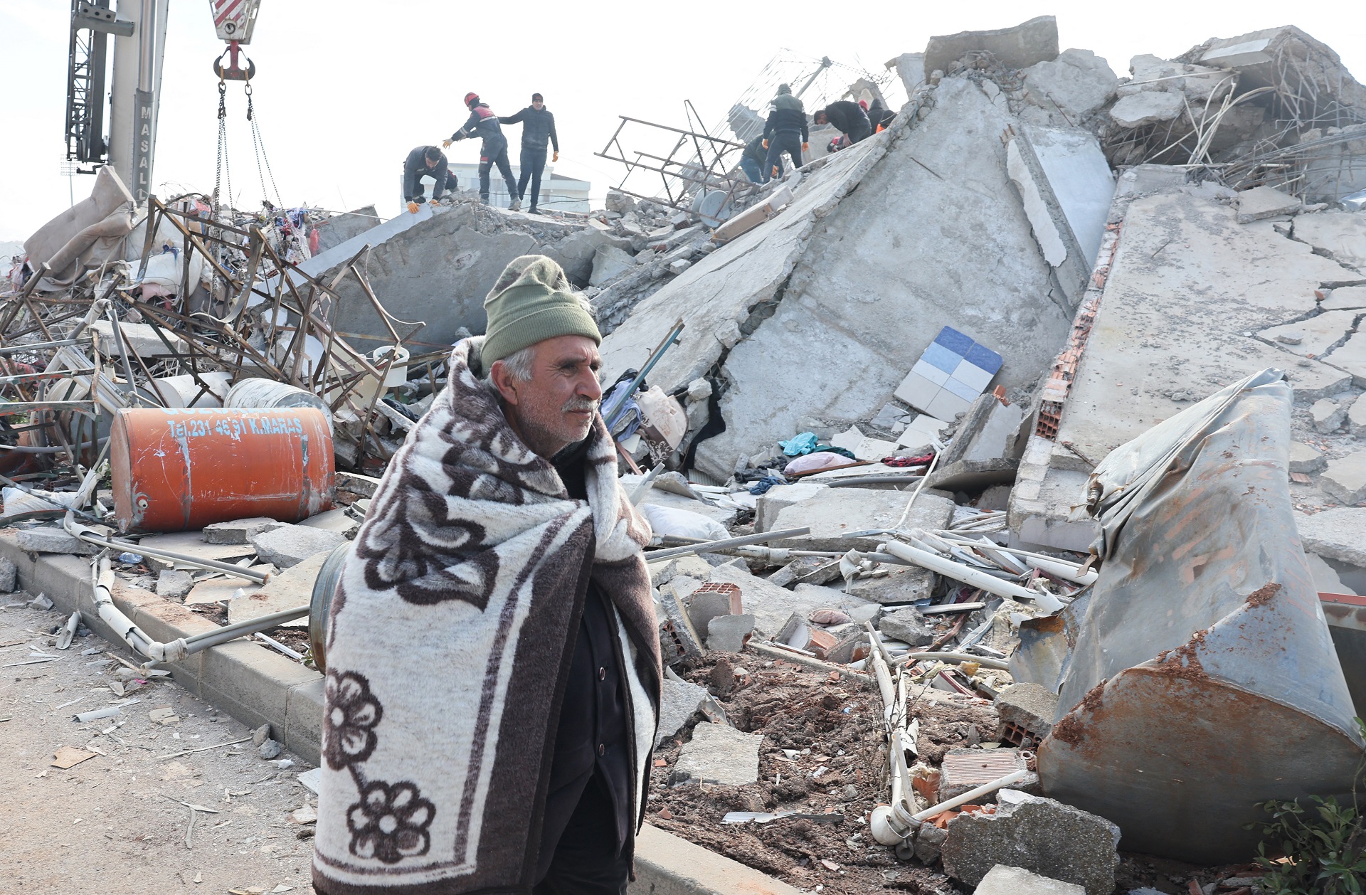 Un hombre camina entre los escombros del terremoto con una frazada de abrigo (AFP)