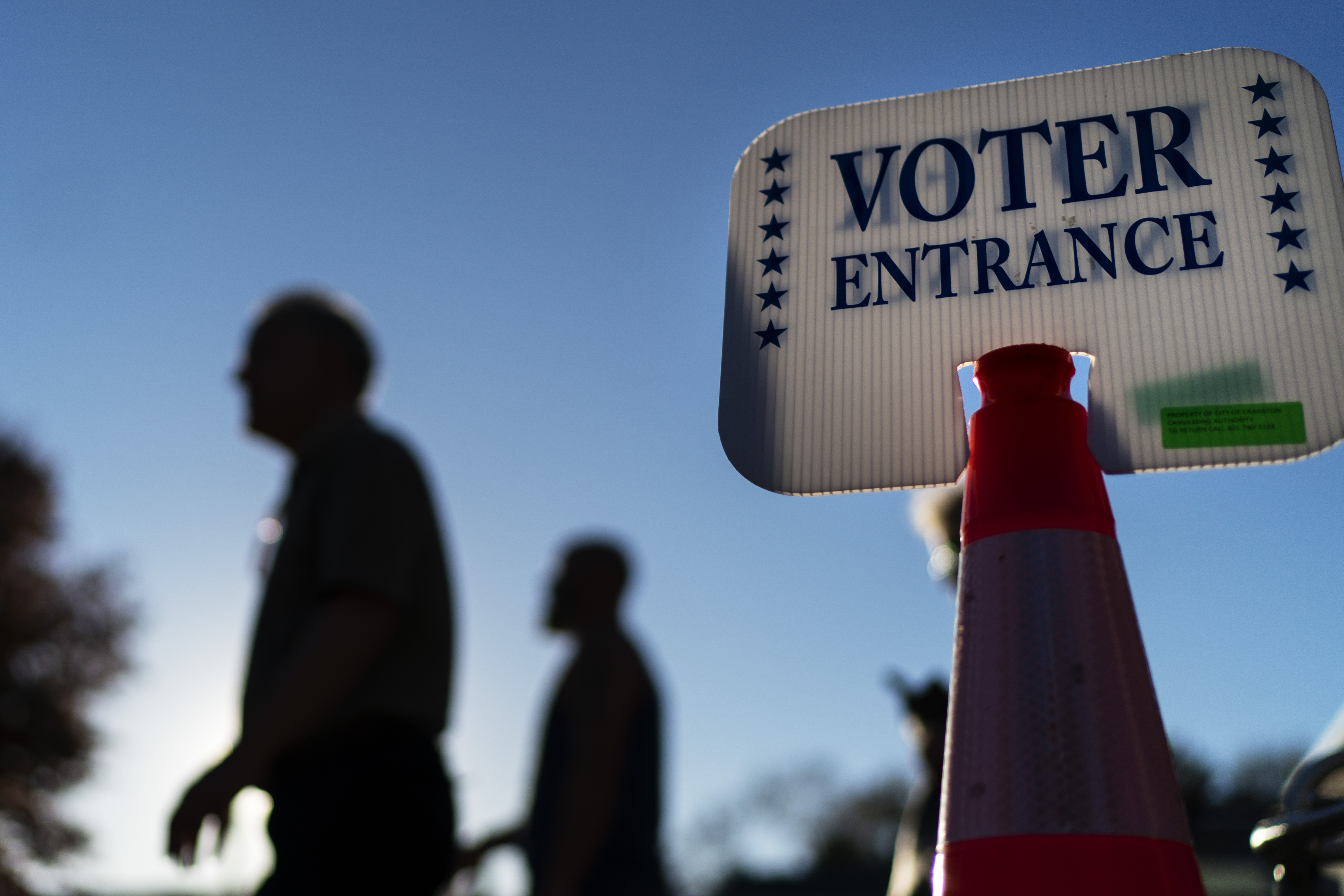 Los votantes pasan un letrero afuera de un sitio de votación en Warwick, Rhode Island, el lunes 7 de noviembre de 2022, después de emitir sus votos el último día de votación anticipada antes de las elecciones de mitad de período. (Foto AP/David Goldman)