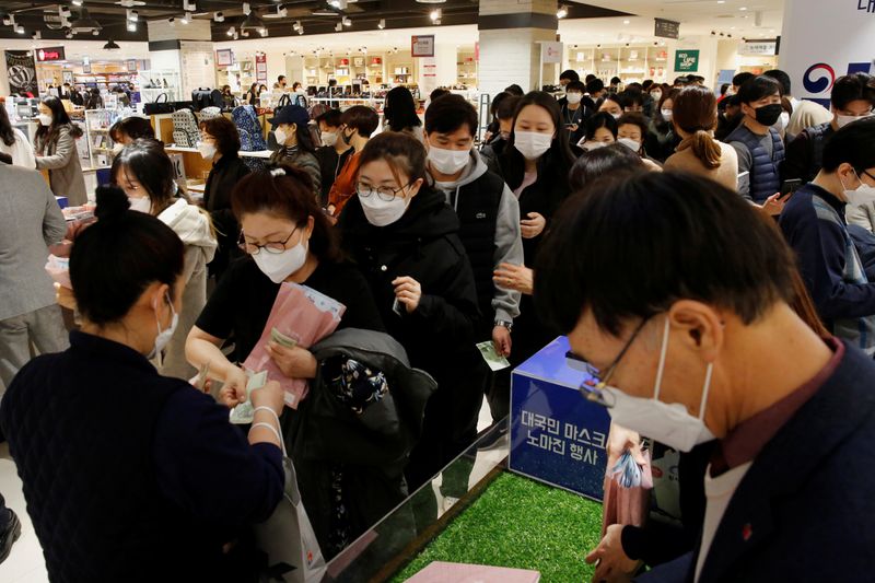 Las personas usan mascarillas para prevenir el contagio del coronavirus en una fila para comprar mascarillas en una tienda de departamentos en Seúl, Corea del Sur