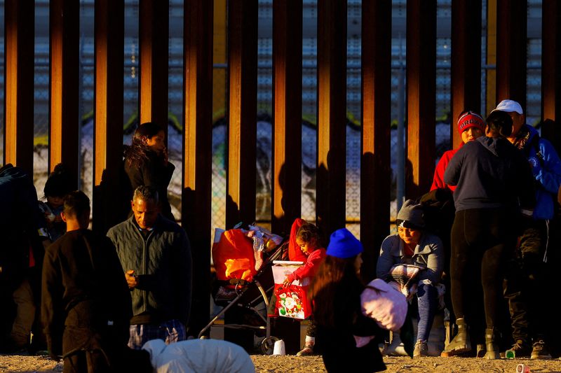 Una niña migrante sostiene un regalo de Navidad mientras hace fila con su familia cerca del muro fronterizo para solicitar asilo en El Paso, Texas, EEUU, vista desde Ciudad Juárez, México, el 25 de diciembre de 2022. (REUTERS/José Luis González)