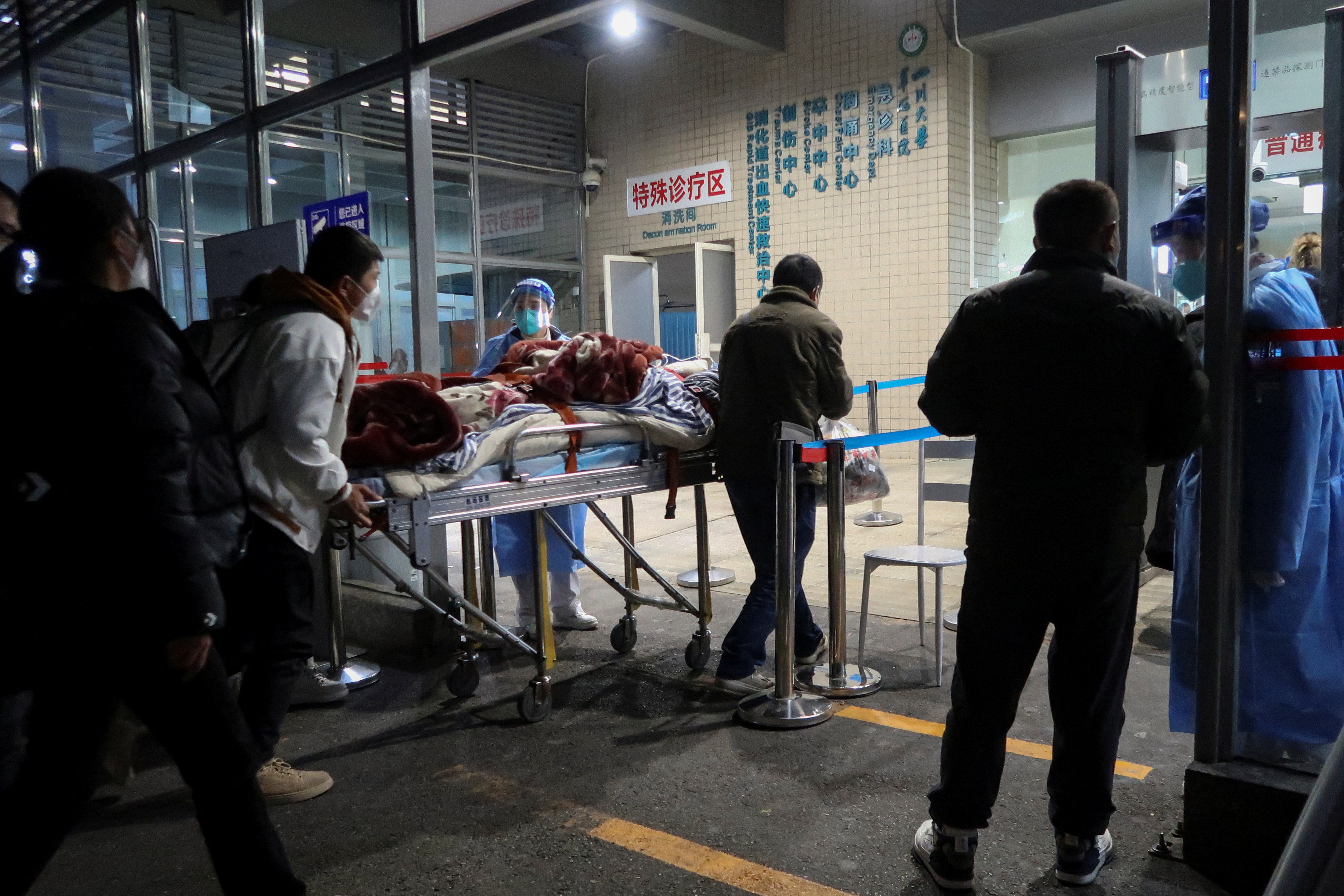 Personas transportan a un paciente anciano en una camilla fuera del departamento de emergencias de un hospital, en medio del brote de la enfermedad del coronavirus (COVID-19), en Chengdu, provincia de Sichuan, China