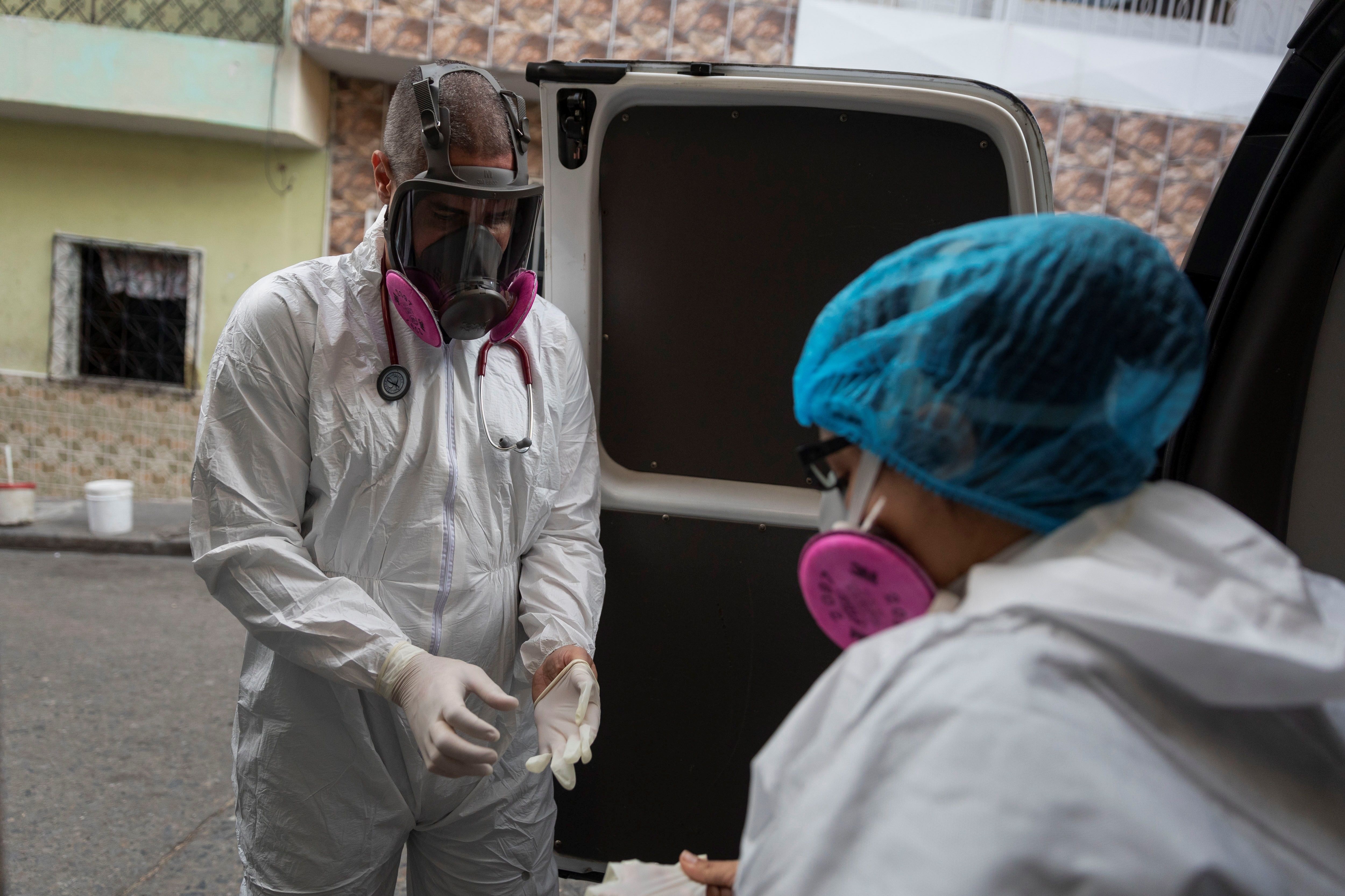 Los paramédicos de Ángeles de las Vías, Zully Rodríz (d) y Jonathan Quantip (i), se preparan para atender a un paciente con COVID-19 en su domicilio, el 22 de abril, en Caracas (Venezuela). EFE/ Rayner Peña R.
