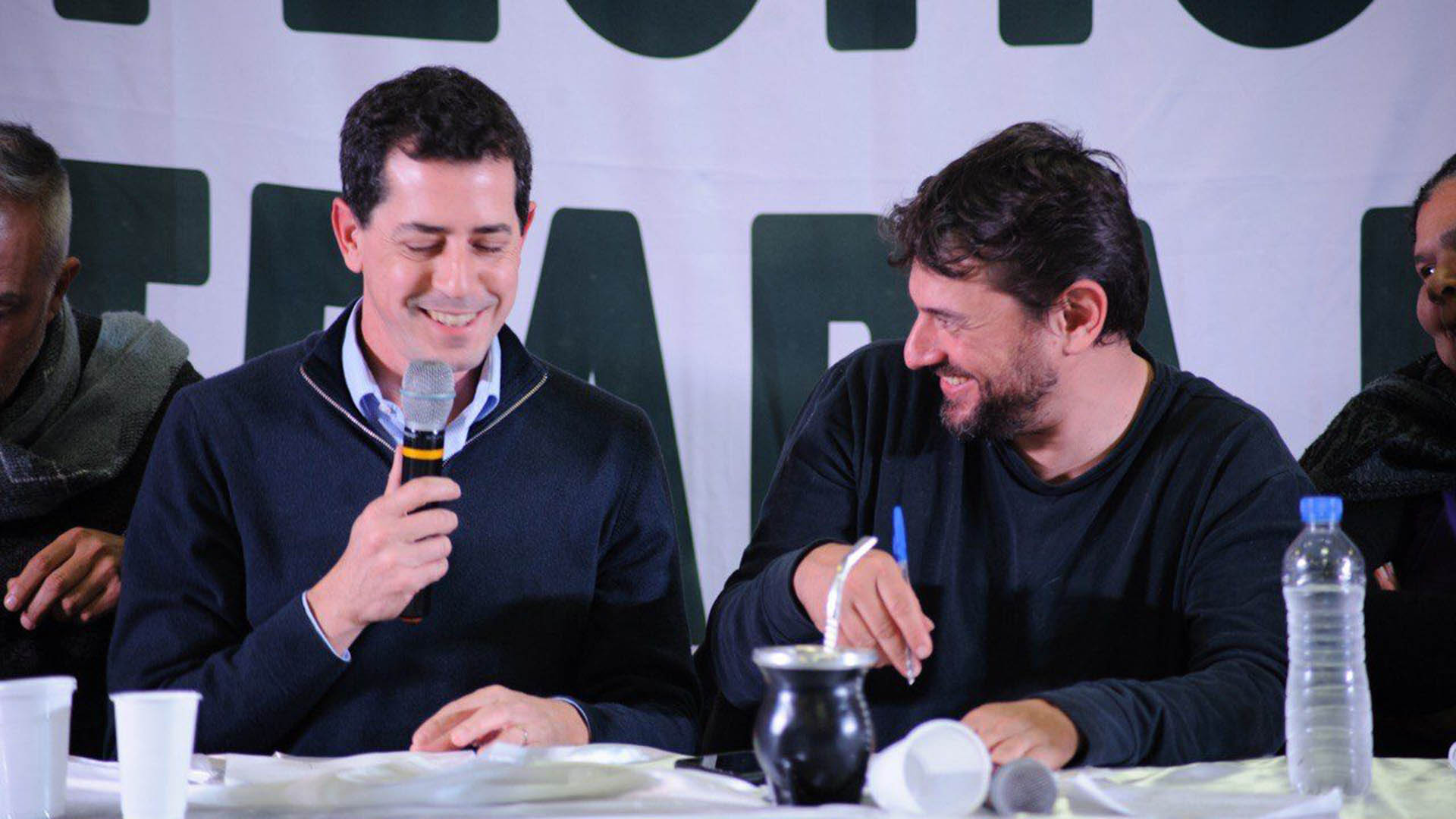 Eduardo Wado De Pedro y Juan Grabois sonríen durante un acto partidario