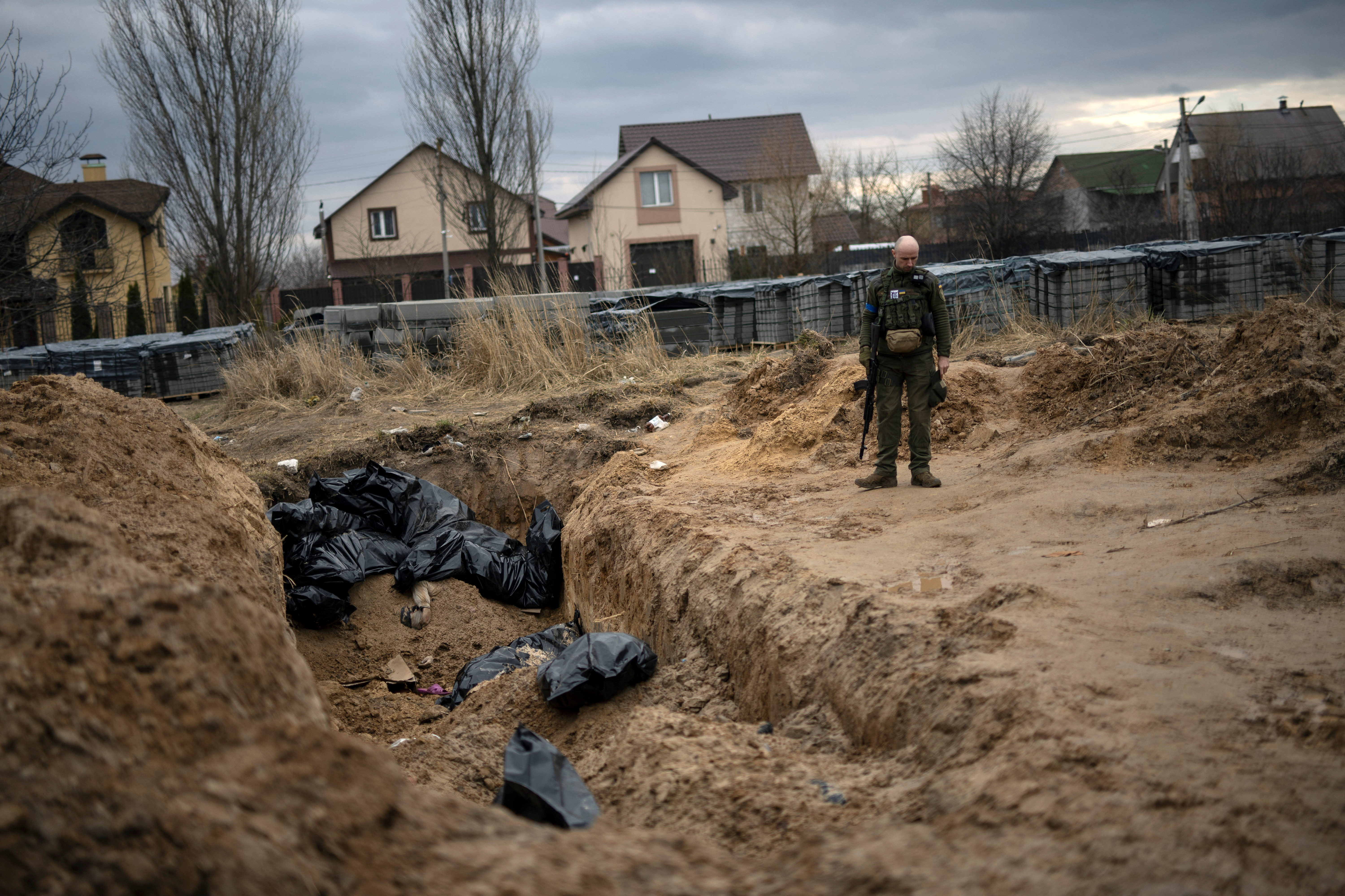 Ukrainian soldier reacts after paying his respects next to a mass grave with bodies of civilians in Bucha