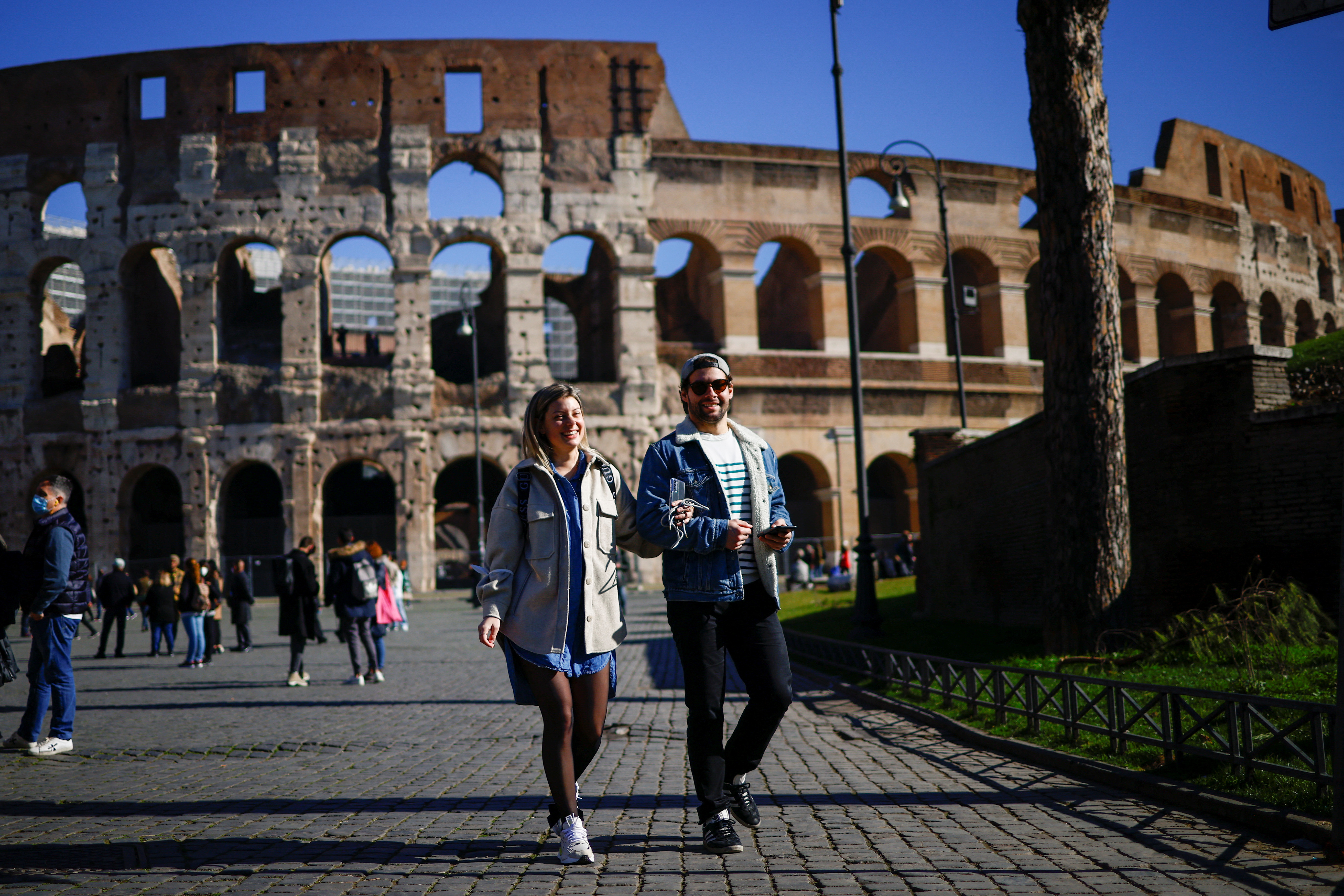 La gente camina cerca del Coliseo sin usar máscaras faciales el día que el gobierno de Italia eliminó la obligación de usar máscaras al aire libre luego de una disminución en los casos de la enfermedad por coronavirus (COVID-19), en Roma, Italia, el 11 de febrero de 2022. REUTERS/Guglielmo Mangiapane
