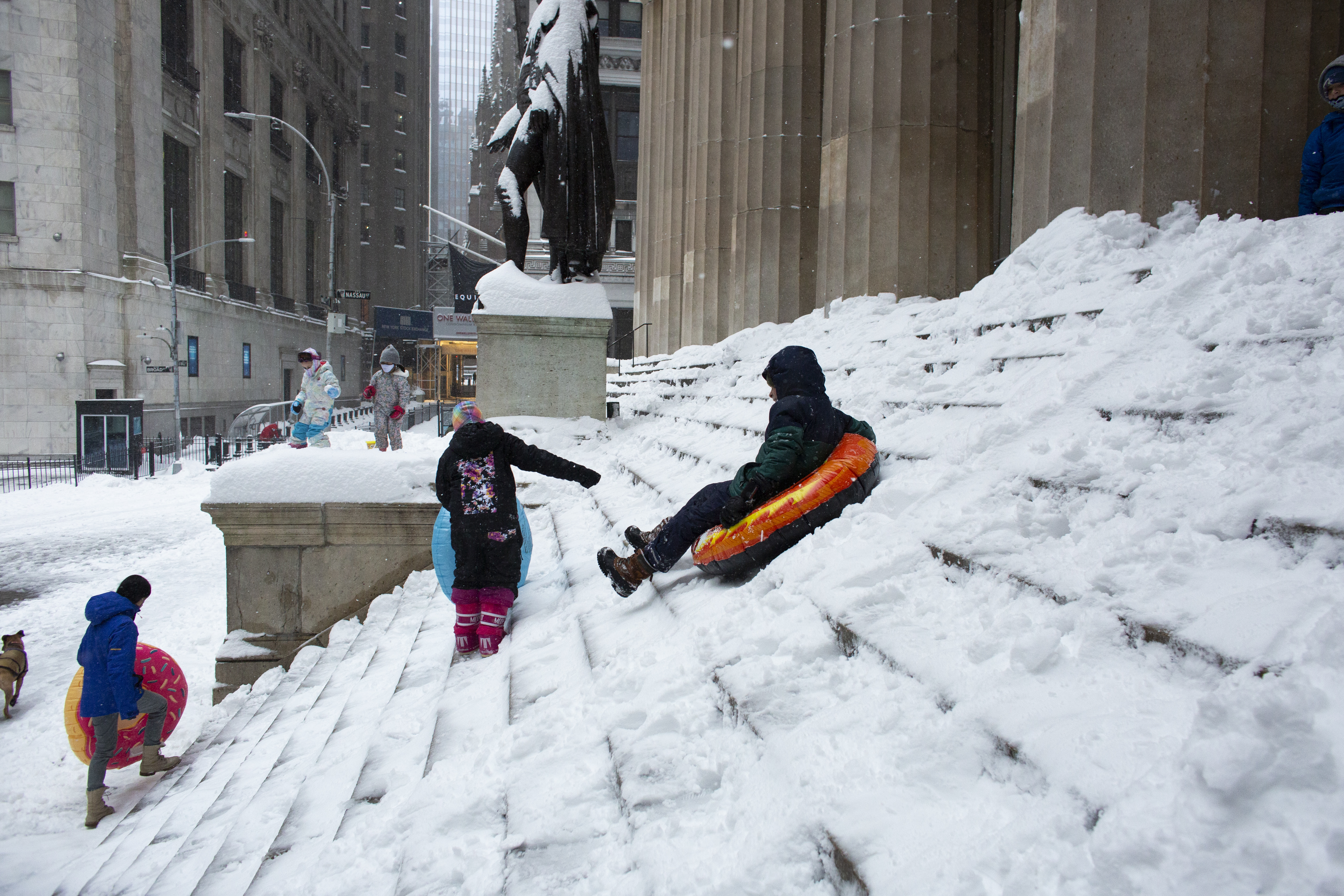 Personas juegan con la nieve frente al edificio de la bolsa de Wall Street. (Kena Betancur / AFP)