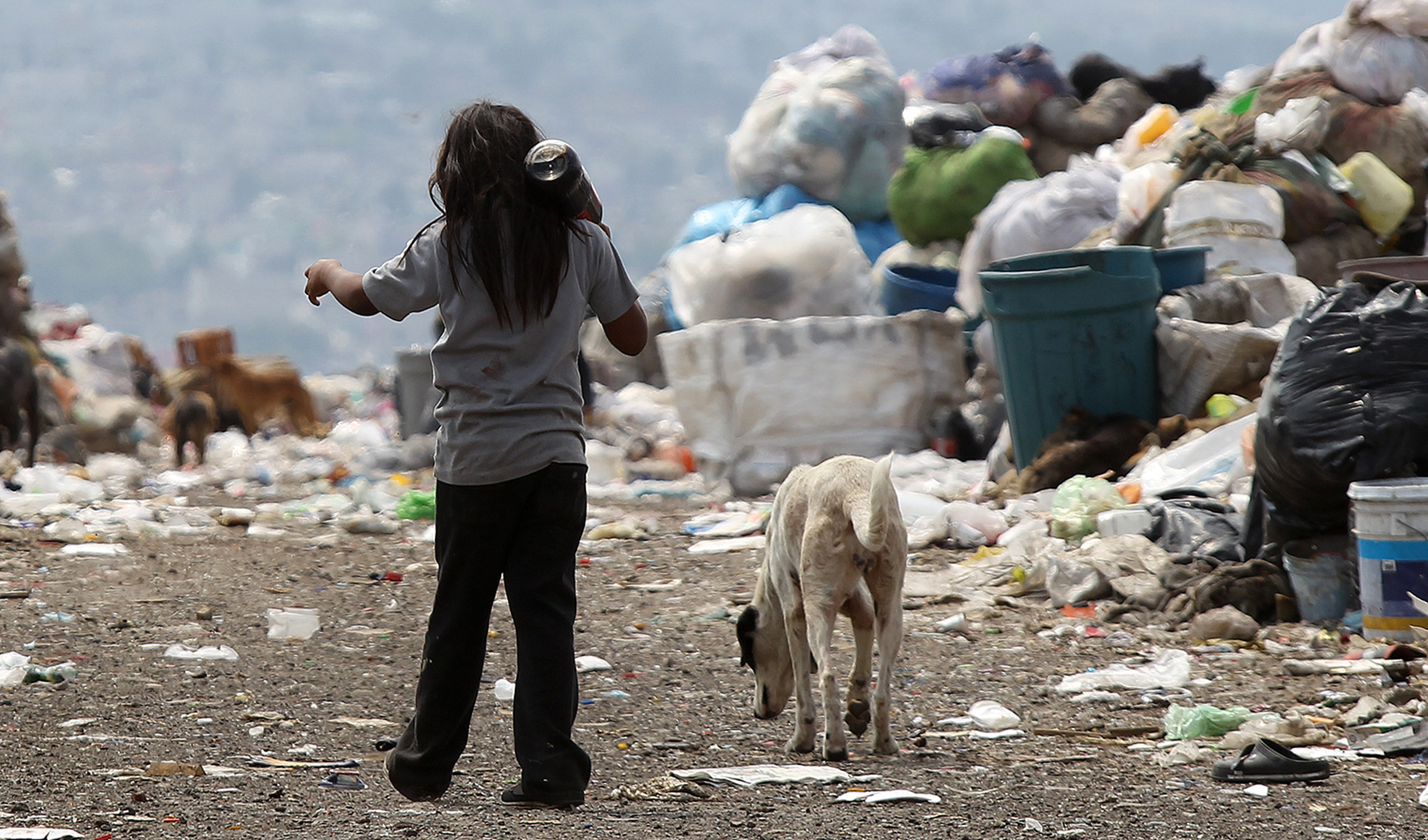 Fotografía del 18 de abril de 2017 de un niño con su perro caminando rumbo a su casa entre montañas de basura en el vertedero municipal del Bordo de Xochiaca, en Ciudad Nezahualcoyotl (México). EFE/Alex Cruz/Archivo
