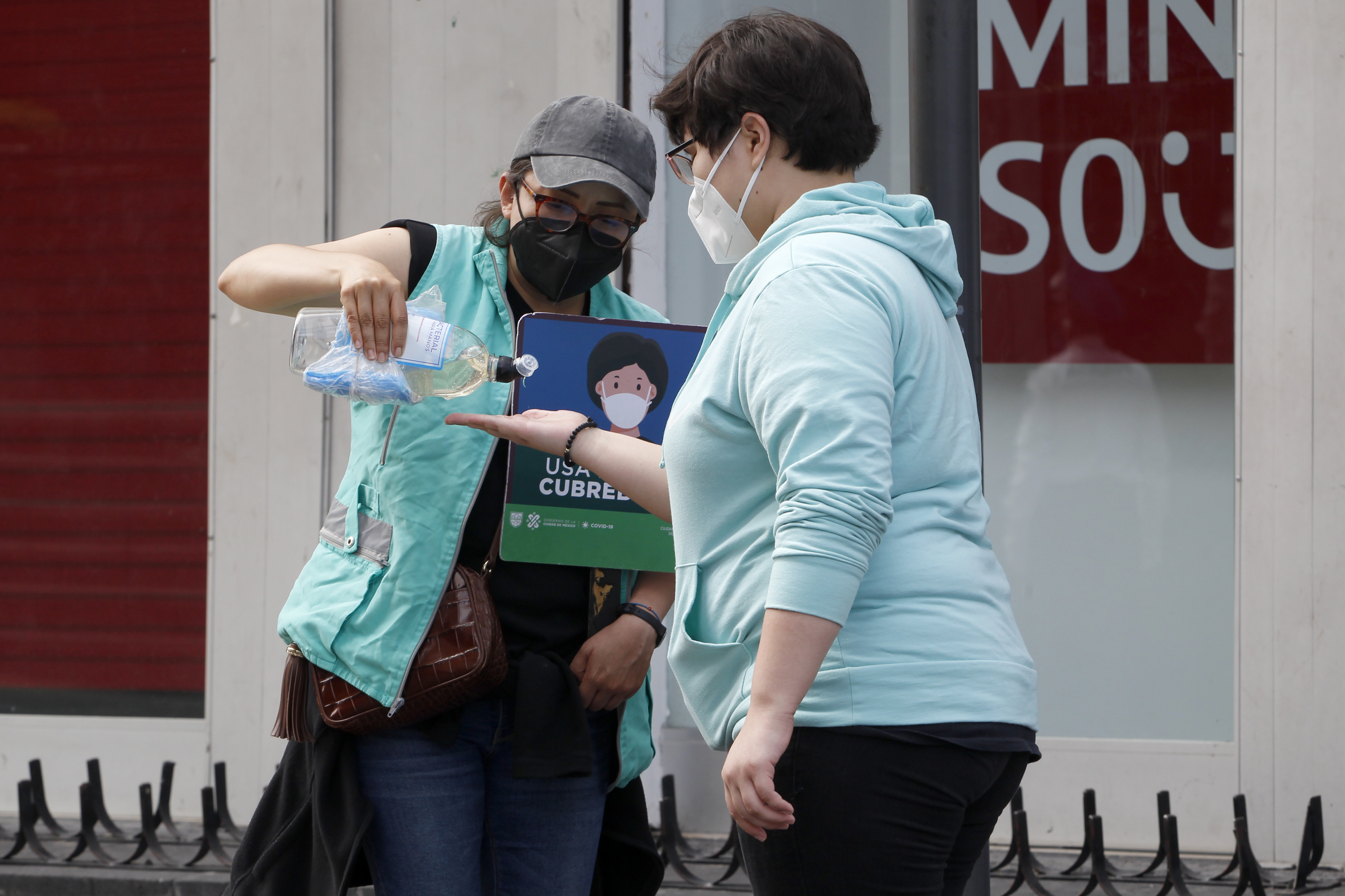 Una mujer aplica gel antibacterial a otra antes de entrar a la calle de Madero, en el centro Histórico. 
Foto: Karina Hernández / Infobae 