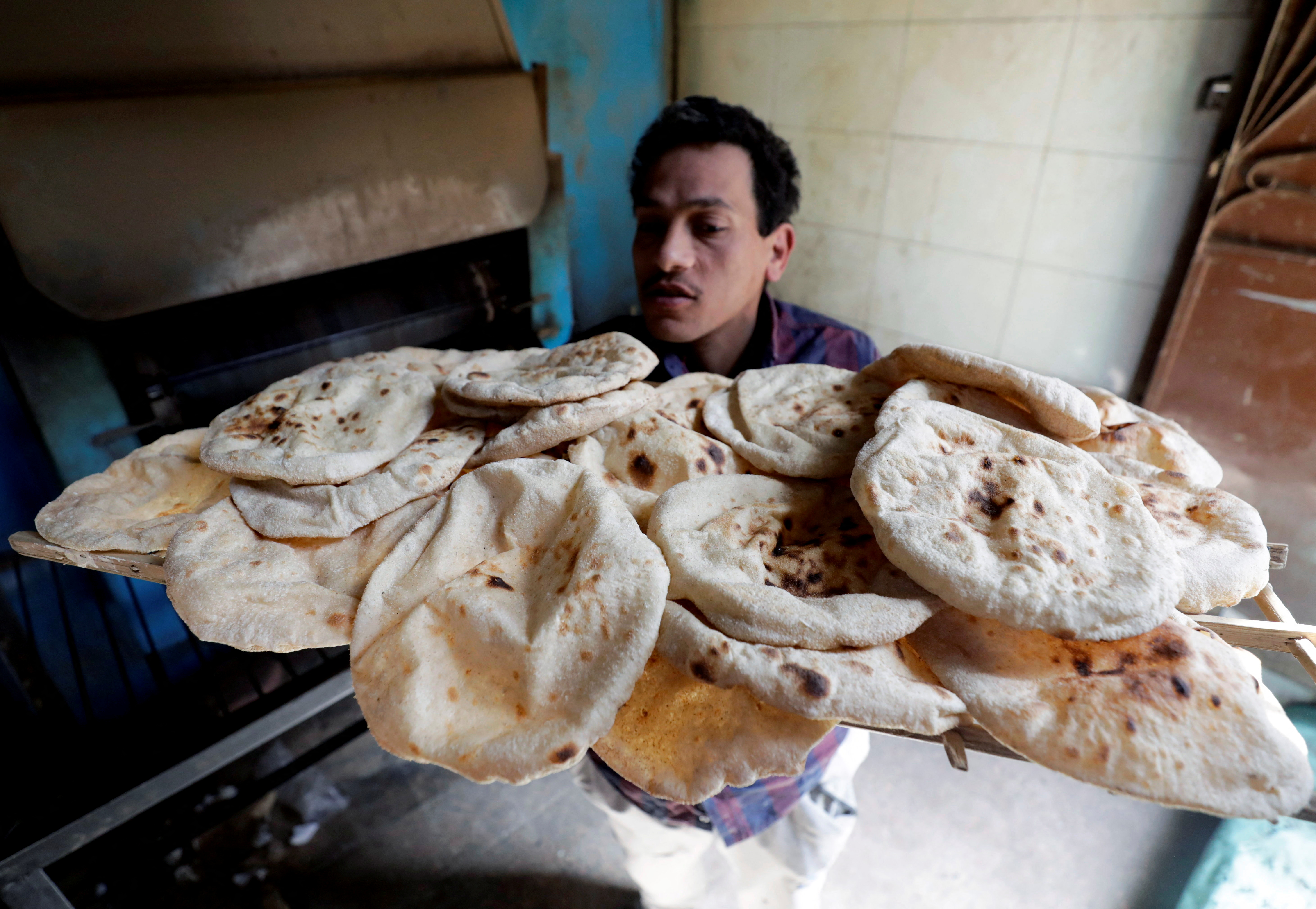 Un panadero saca la primera horneada de pan pita en El-Kalubia, al noreste de El Cairo. El aumento del precio de la harina hizo subir el precio del pan y el descontento social. REUTERS/Mohamed Abd El Ghany