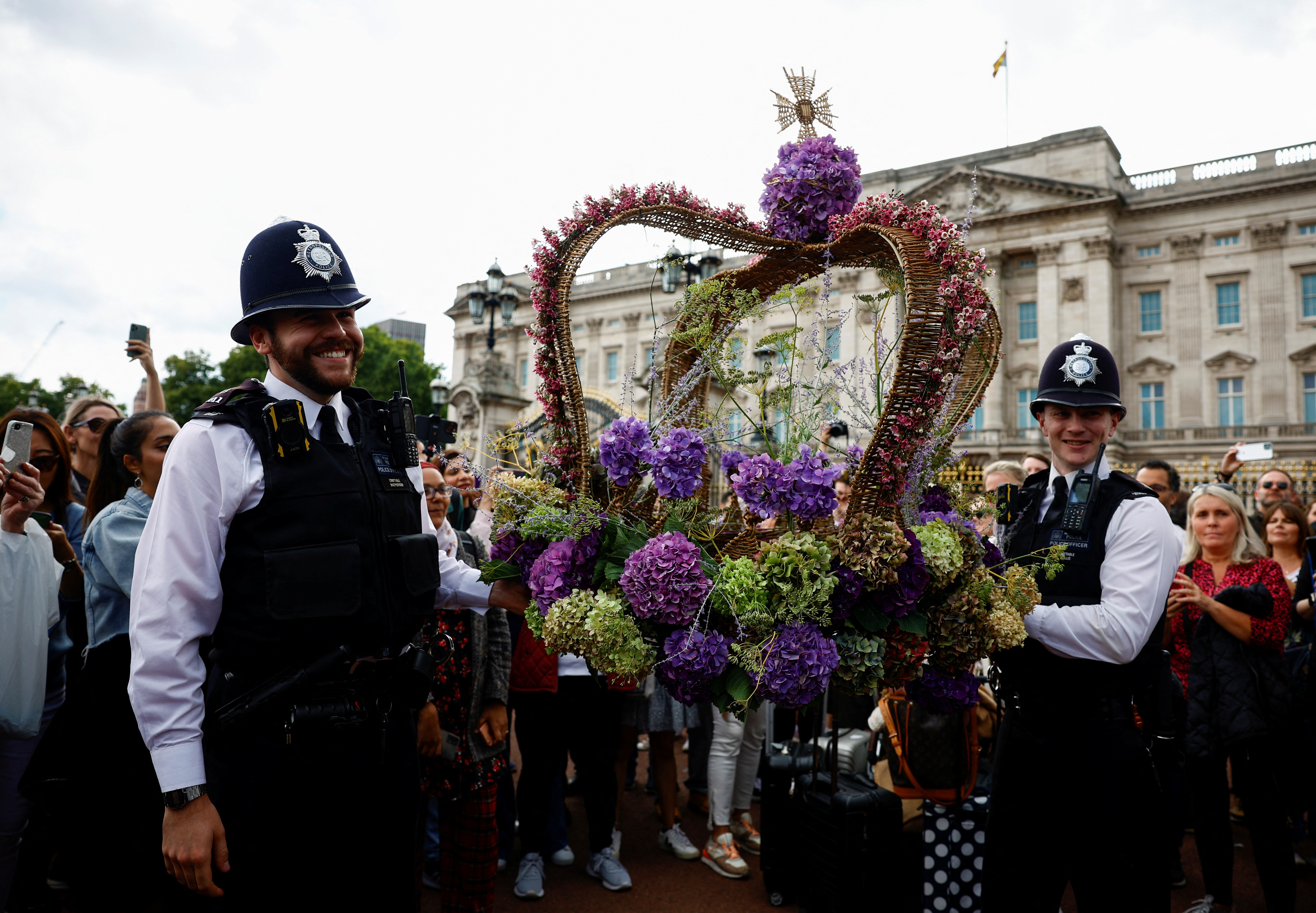 Dos policías sostienen una corona con flores (REUTERS/Sarah Meyssonnier)