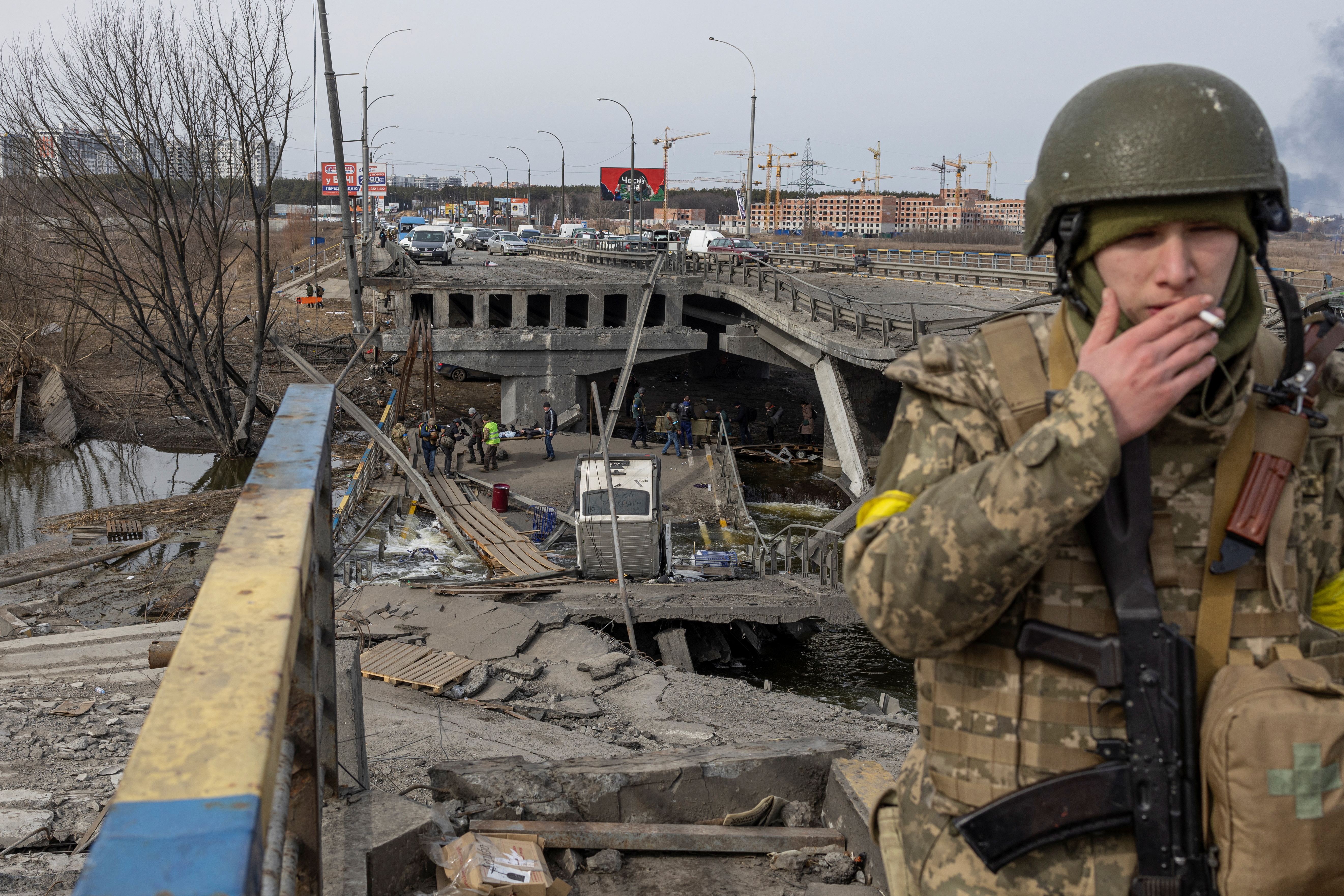 Militares ucranianos, al fondo, evacuan a personas de la ciudad de Irpin, a las afueras de Kiev, Ucrania, el 12 de marzo de 2022 (REUTERS/Marko Djurica)