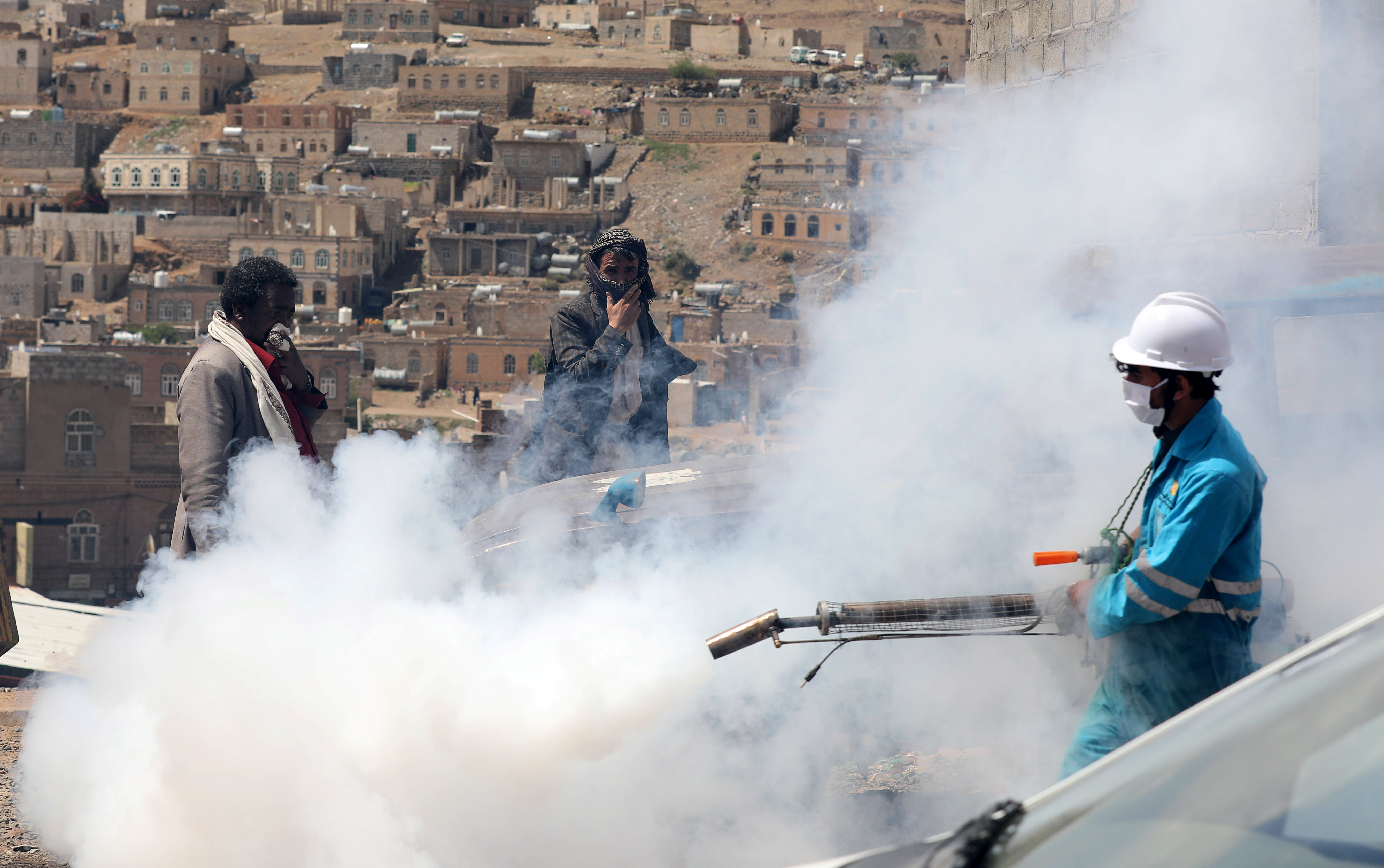 La gente se cubre el rostro mientras un trabajador de la salud fumiga una zona residencial durante una campaña de fumigación mientras continúa la propagación de la enfermedad coronavirus (COVID-19), en las afueras de Sanaa, Yemen, el 13 de abril de 2020. REUTERS/Khaled Abdullah