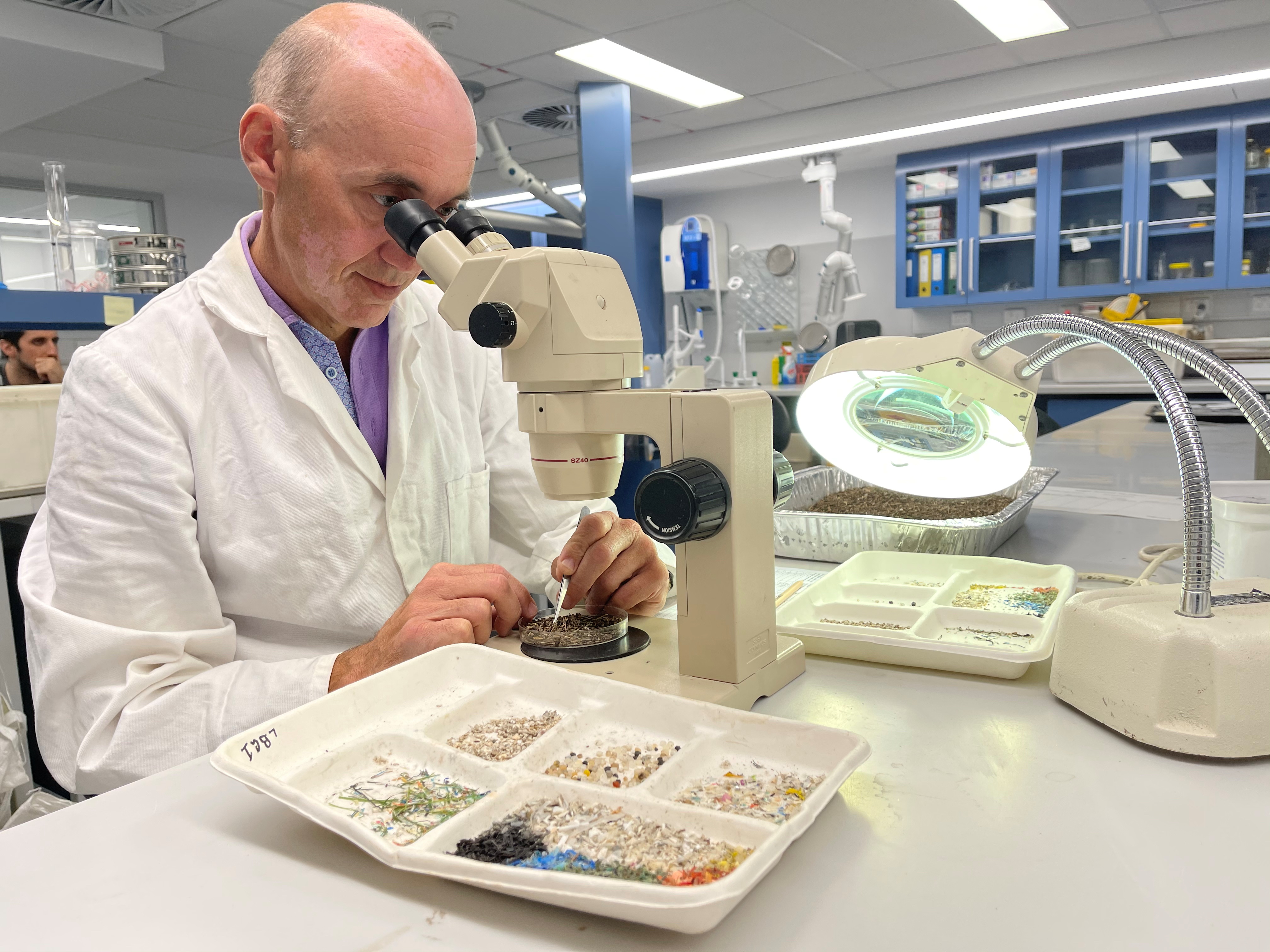 El doctor Scott Wilson de la Universidad de Macquarie, en Sydney, Australia observa bajo el microscopio los microsplásticos hallado en las playas locales. (REUTERS/Jill Gralow)