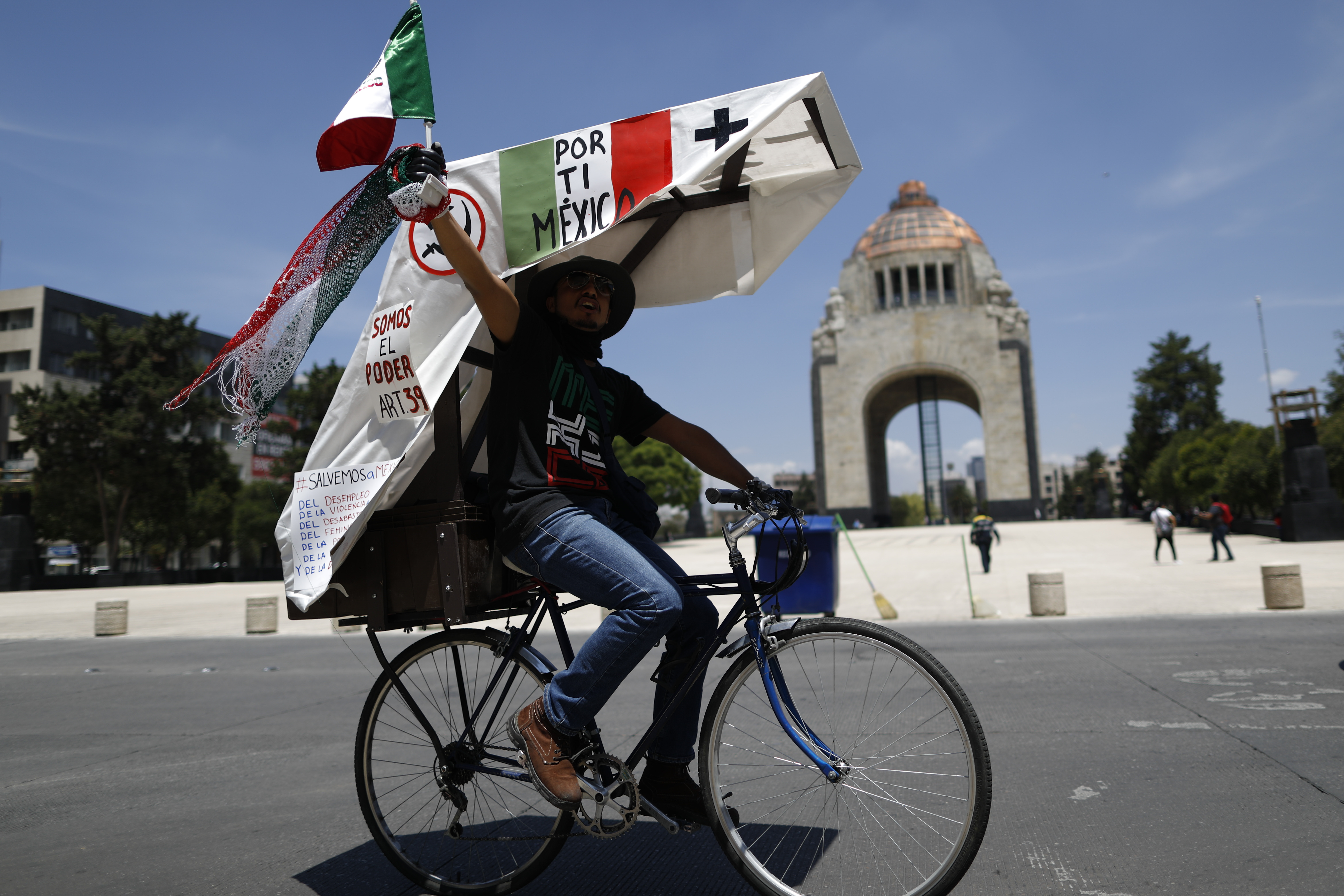 Un hombre en bicicleta participa en una protesta que involucra a cientos de autos pidiendo la renuncia del presidente Andrés Manuel López Obrador, en la Ciudad de México, el domingo 28 de junio de 2020. (Foto AP / Rebecca Blackwell)