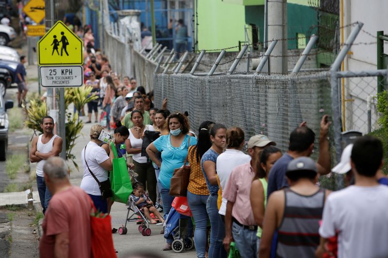 Personas esperan en un punto de distribución de frutas y verduras donadas por productores nacionales que no pueden exportar debido a la pandemia del coronavirus, en San José, Costa Rica el 13 de abril de 2020 (Reuters/ Juan Carlos Ulate)