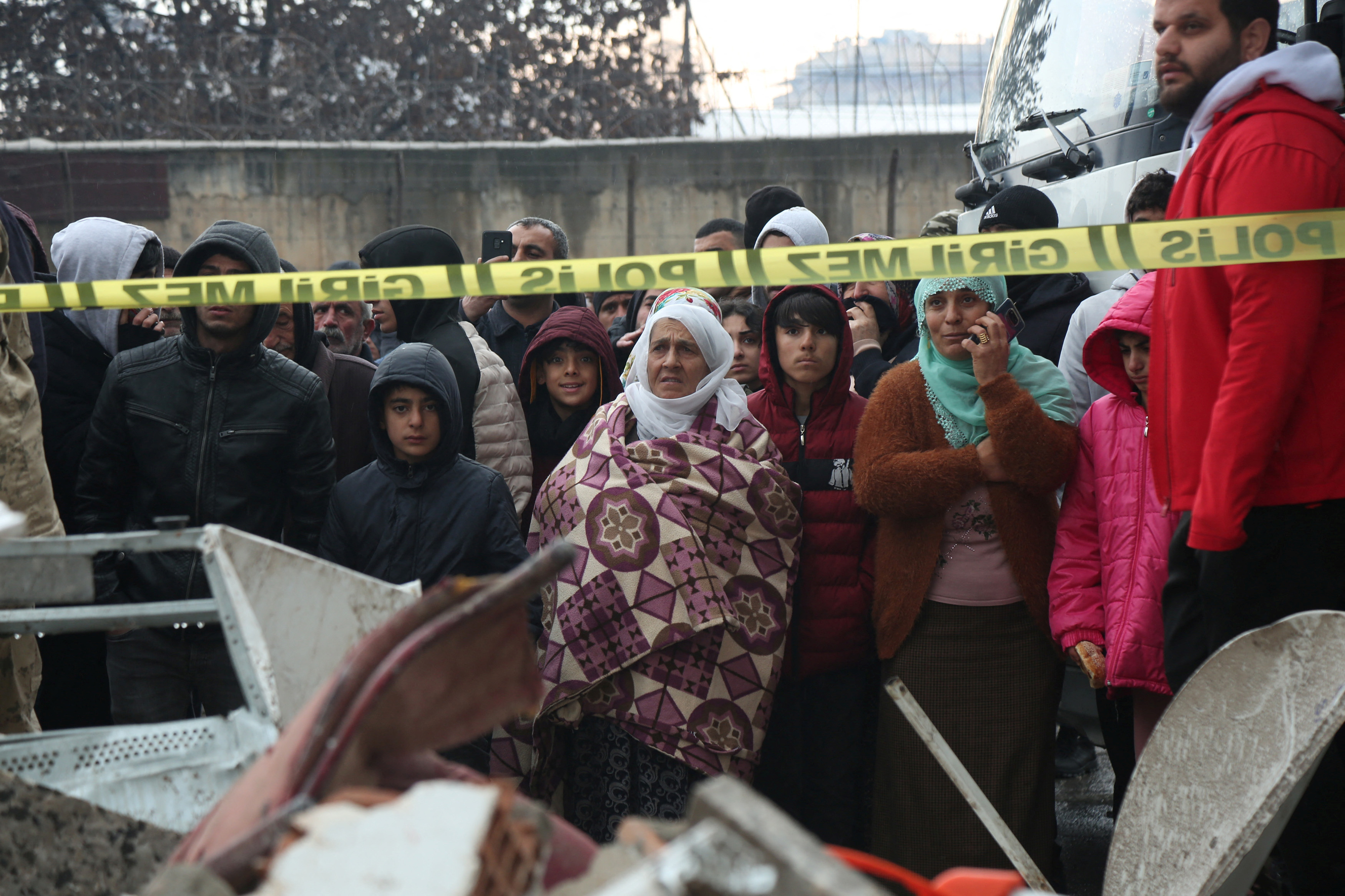 Víctimas del terremoto se juntan tras una cinta policial mientras ven el desastre que quedó en Diyarbakir, Turquía.