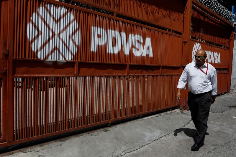 Un hombre pasa junto a un portón con el logo corporativo de la petrolera estatal PDVSA en Caracas (REUTERS/Marco Bello/Archivo)