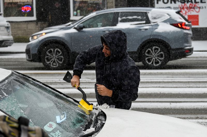 Un conducente rimuove la neve dalla sua auto mentre sperimenta il freddo mentre un fenomeno atmosferico noto come un tornado di bombe colpisce il paese, a Chicago, Illinois, USA.