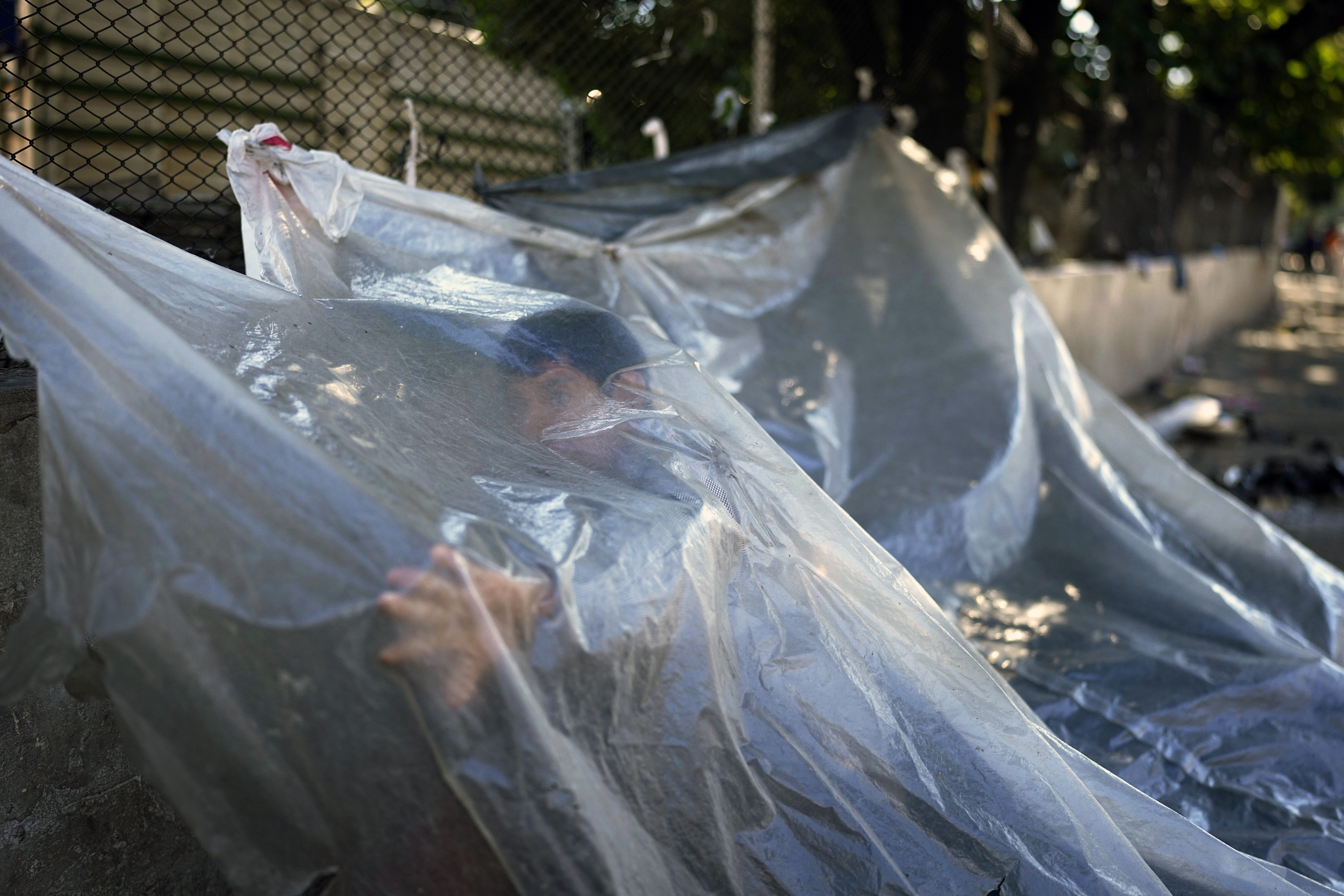 Pablo Fernández, an indigenous Mb'a from Caaguazu, under a plastic sheet that is part of his camp outside the Paraguayan Indigenous Institute (INDI), where a group of indigenous people are demanding food aid, in Asunción, Paraguay, on April 28, 2023. The first round of Paraguay's general elections is held on April 30.  (AP Photo/Jorge Saenz)