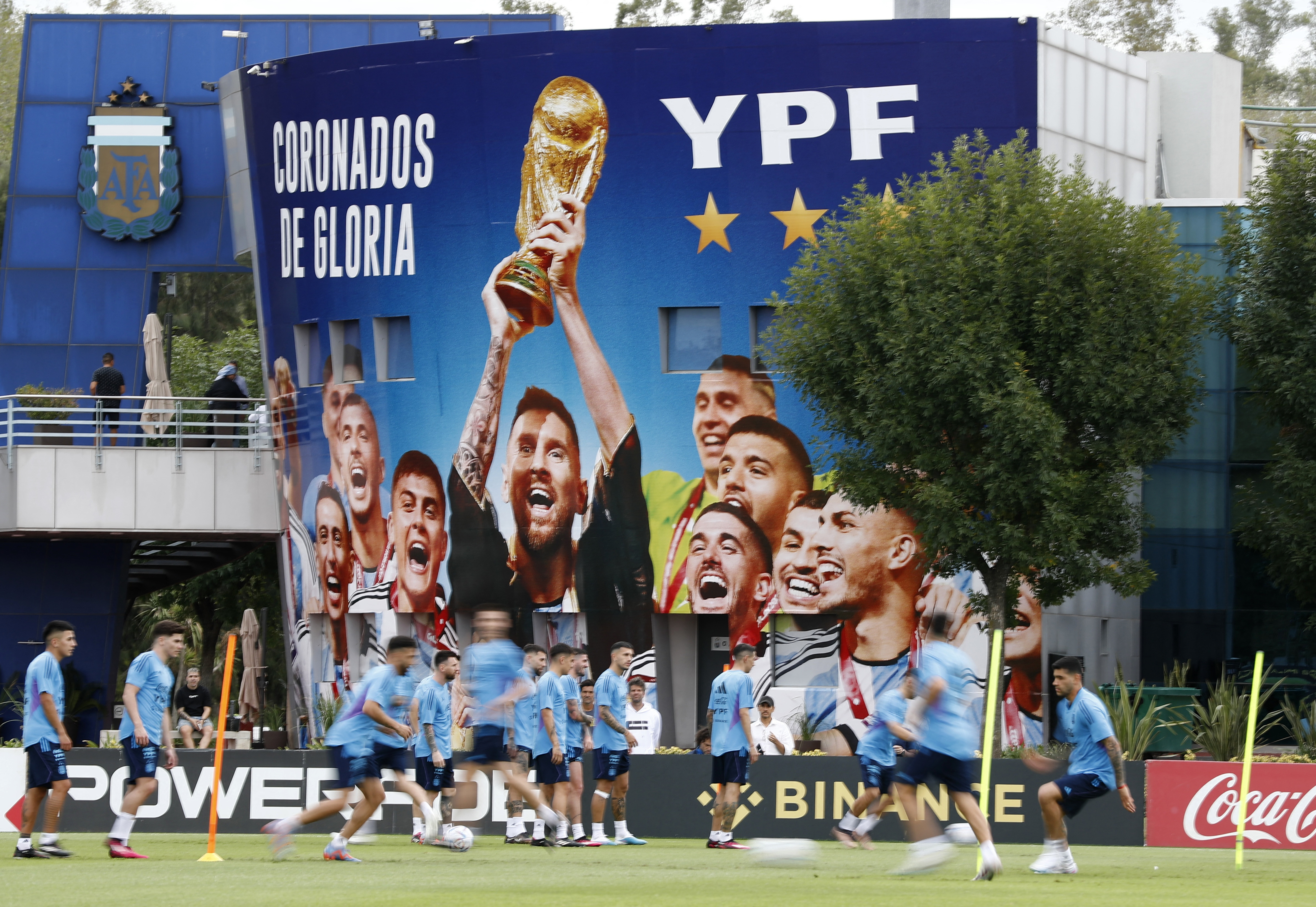 El mural para los campeones y el plantel entrenándose en el predio (Foto: Reuters)