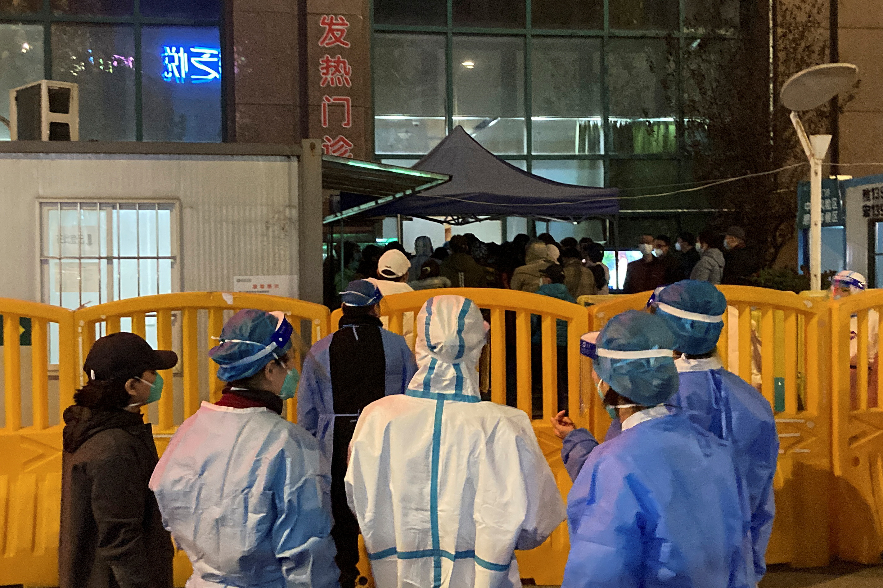 Trabajadores con trajes protectores de pie cerca de las barreras que separa una calle de una cola en el hospital central de Wuhan, después de que el régimen suavizara gradualmente las restricciones sobre el control de la enfermedad por coronavirus (COVID-19), en Wuhan, provincia de Hubei, China 9 de diciembre 2022. REUTERS/Martin Pollard