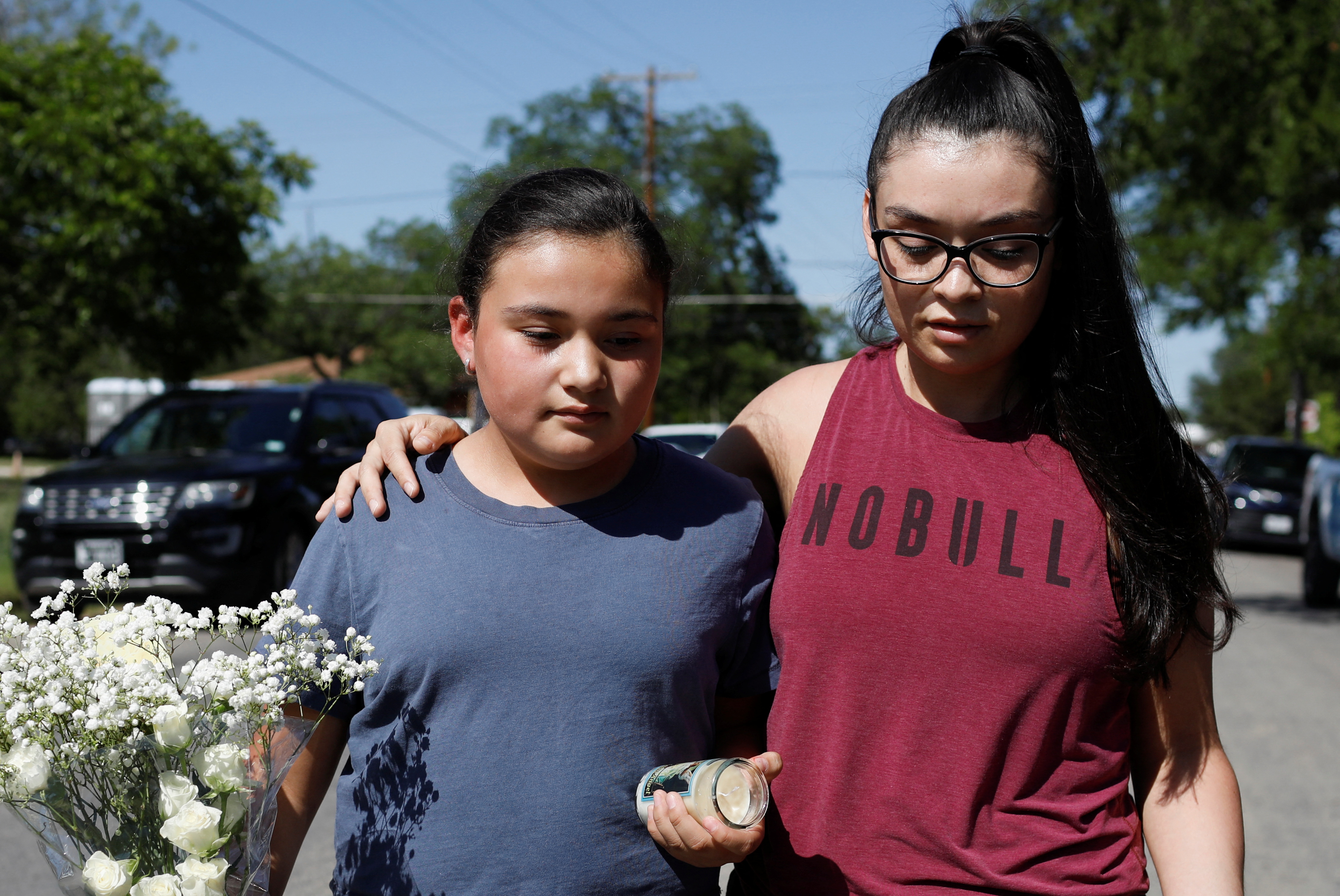 Una niña que estudia en la escuela primaria Robb es acompañada por su madre mientras lleva flores el día después de que un hombre armado matara a 19 niños y dos profesores en la escuela primaria Robb, en el exterior de la escuela primaria Robb, en Uvalde, Texas, Estados Unidos, el 25 de mayo de 2022. REUTERS/Marco Bello