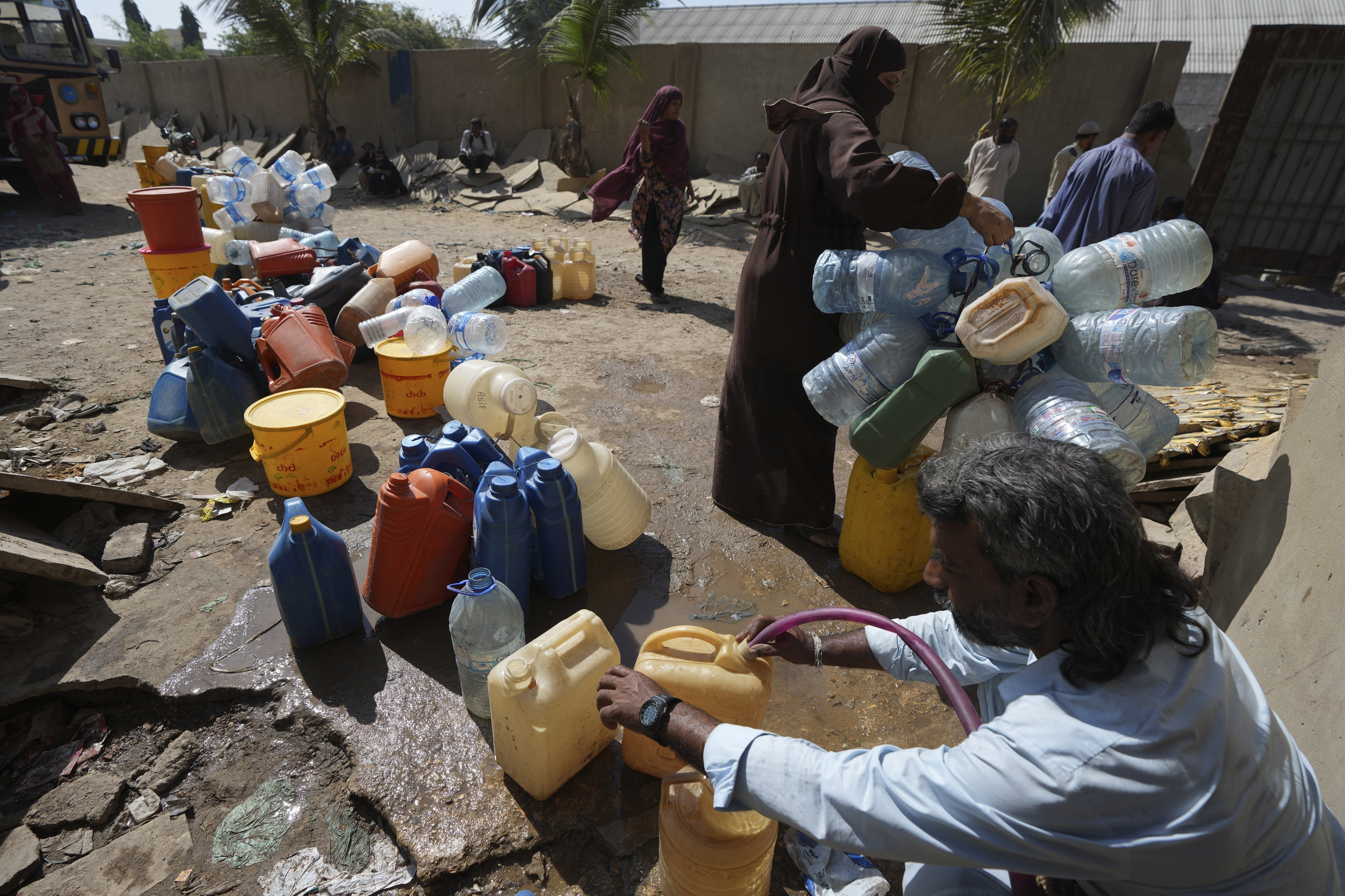 Varias personas recopilan agua potable en un punto de recolección de agua en una barriada, en Karachi, Pakistán, el 21 de marzo de 2023. (AP Foto/Fareed Khan)