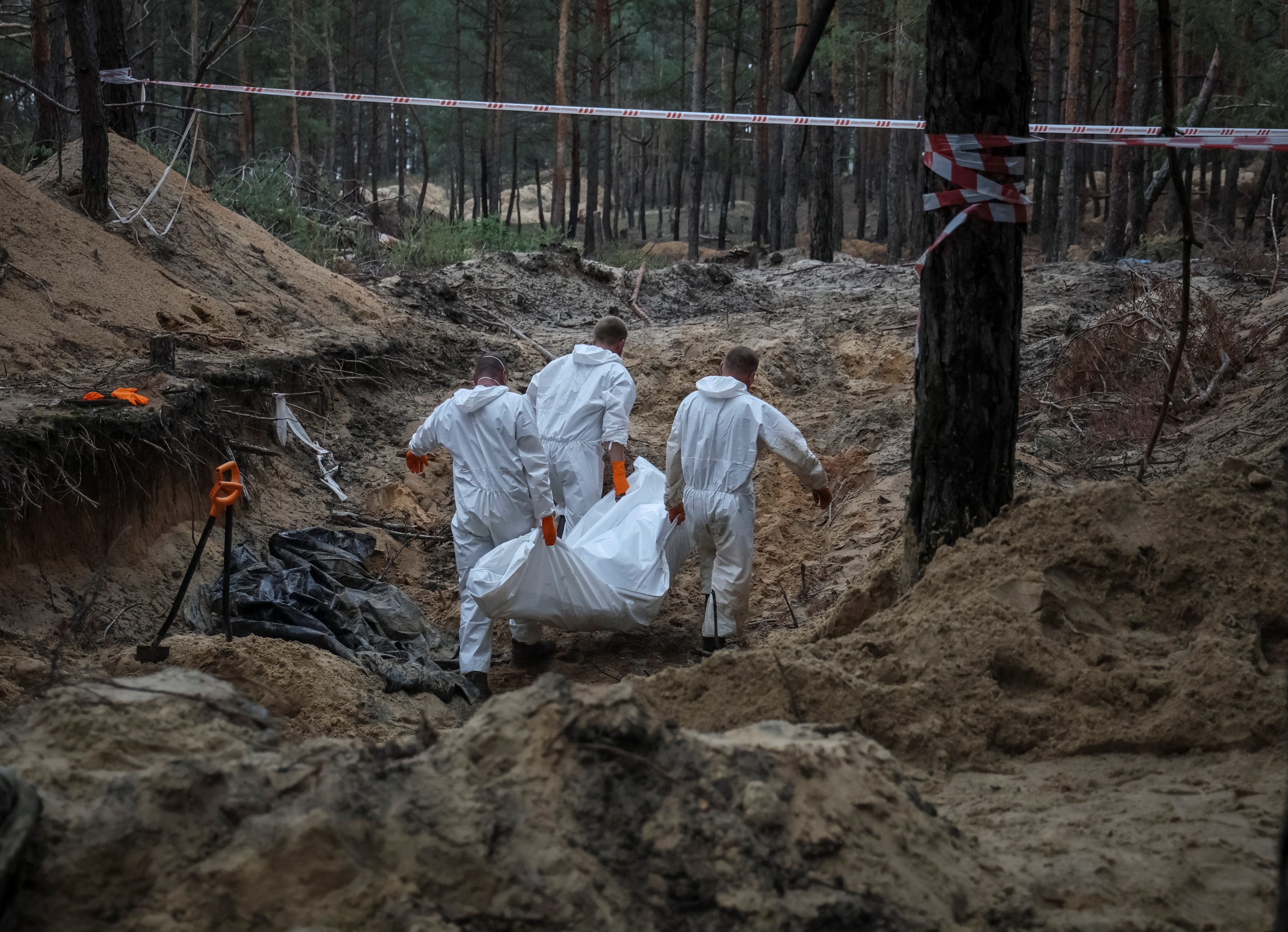 Trabajadores trasladan un cuerpo en Izium (REUTERS/Gleb Garanich)