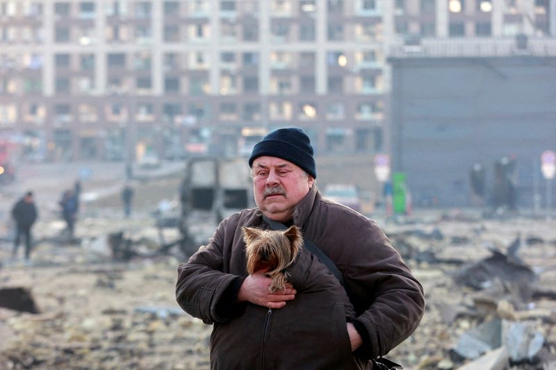 Un hombre lleva un perro en el lugar de un ataque militar a un centro comercial en el distrito Podilskyi de Kiev, mientras continúa la invasión rusa de Ucrania